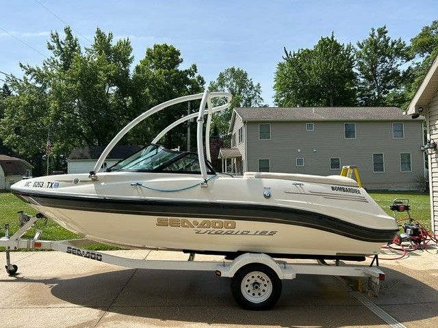 A white Bombardier Sea-Doo boat on a trailer in a residential area.