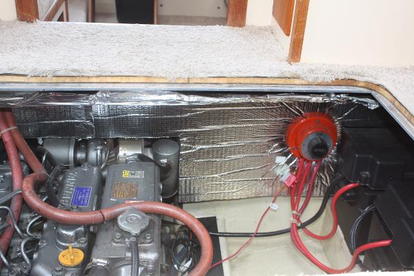 An engine compartment with a motor and cables, surrounded by insulation.