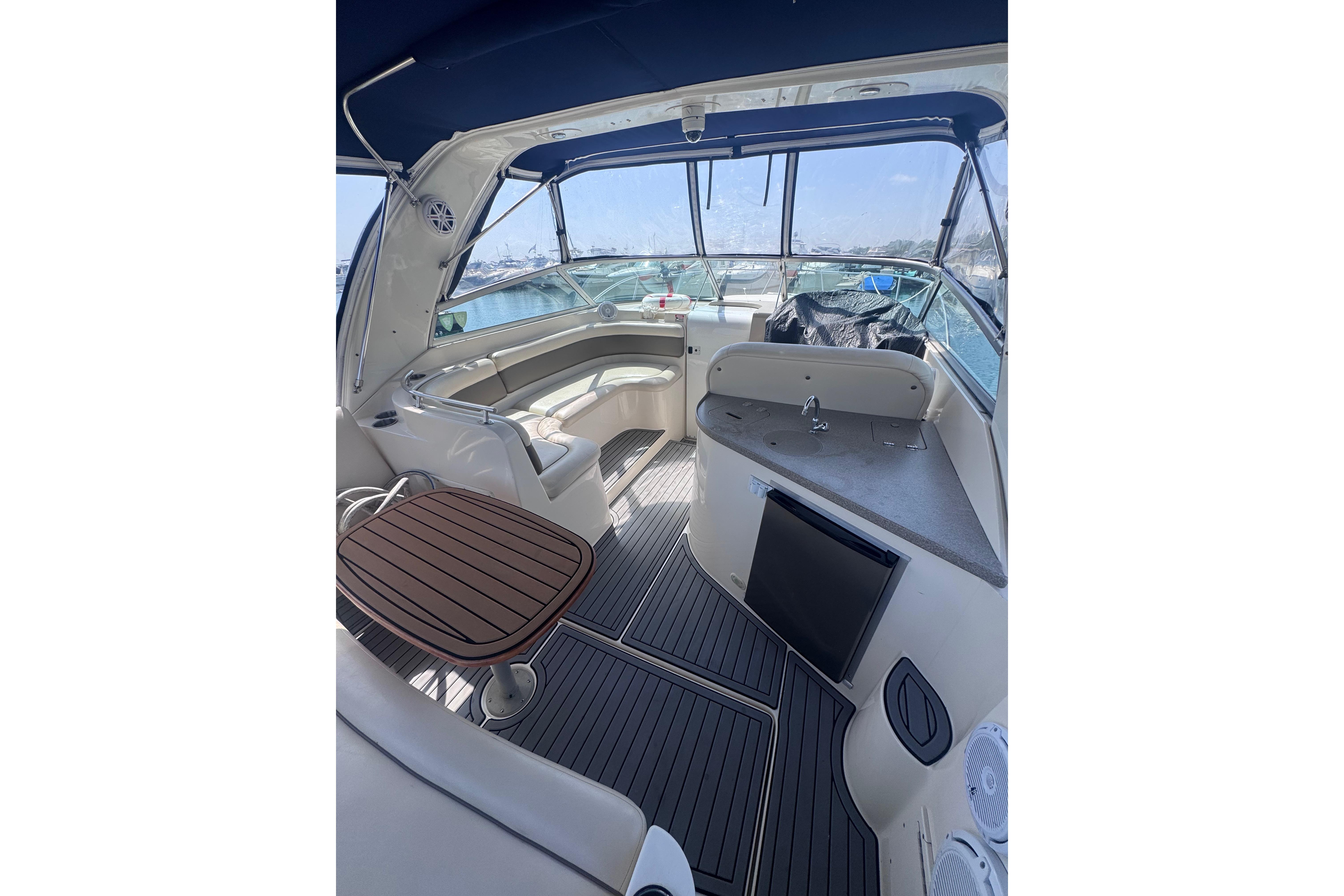2003 Rinker Fiesta Vee 312 boat interior with seating, table, and kitchenette.