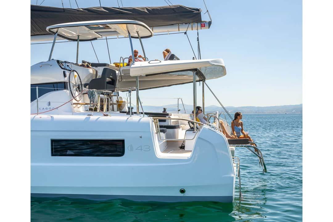 Manufacturer Provided Image: 2026 Lagoon 43 catamaran with people relaxing on deck, sailing in calm blue waters.
