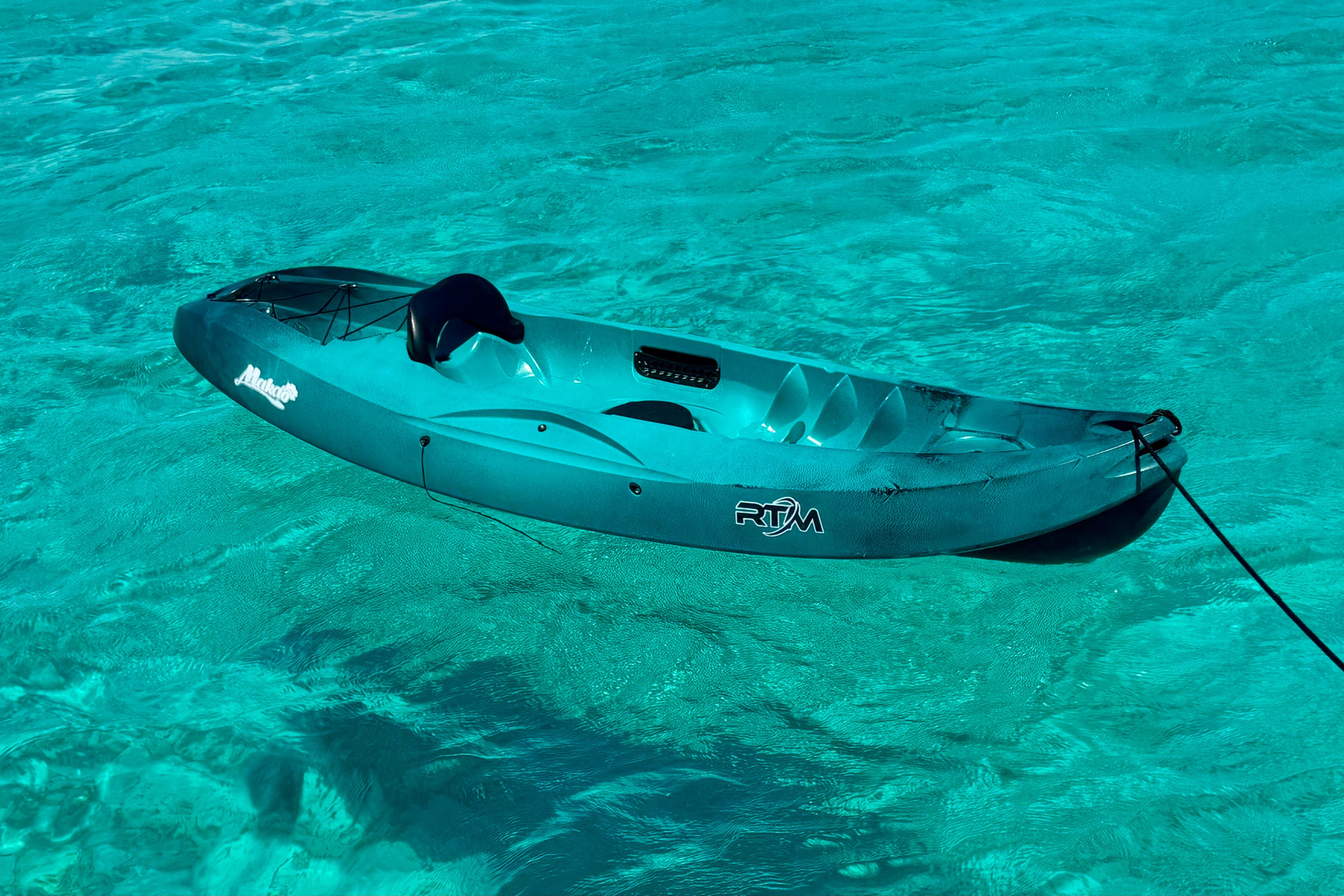 A turquoise kayak floats on clear blue water, showcasing a serene aquatic scene.