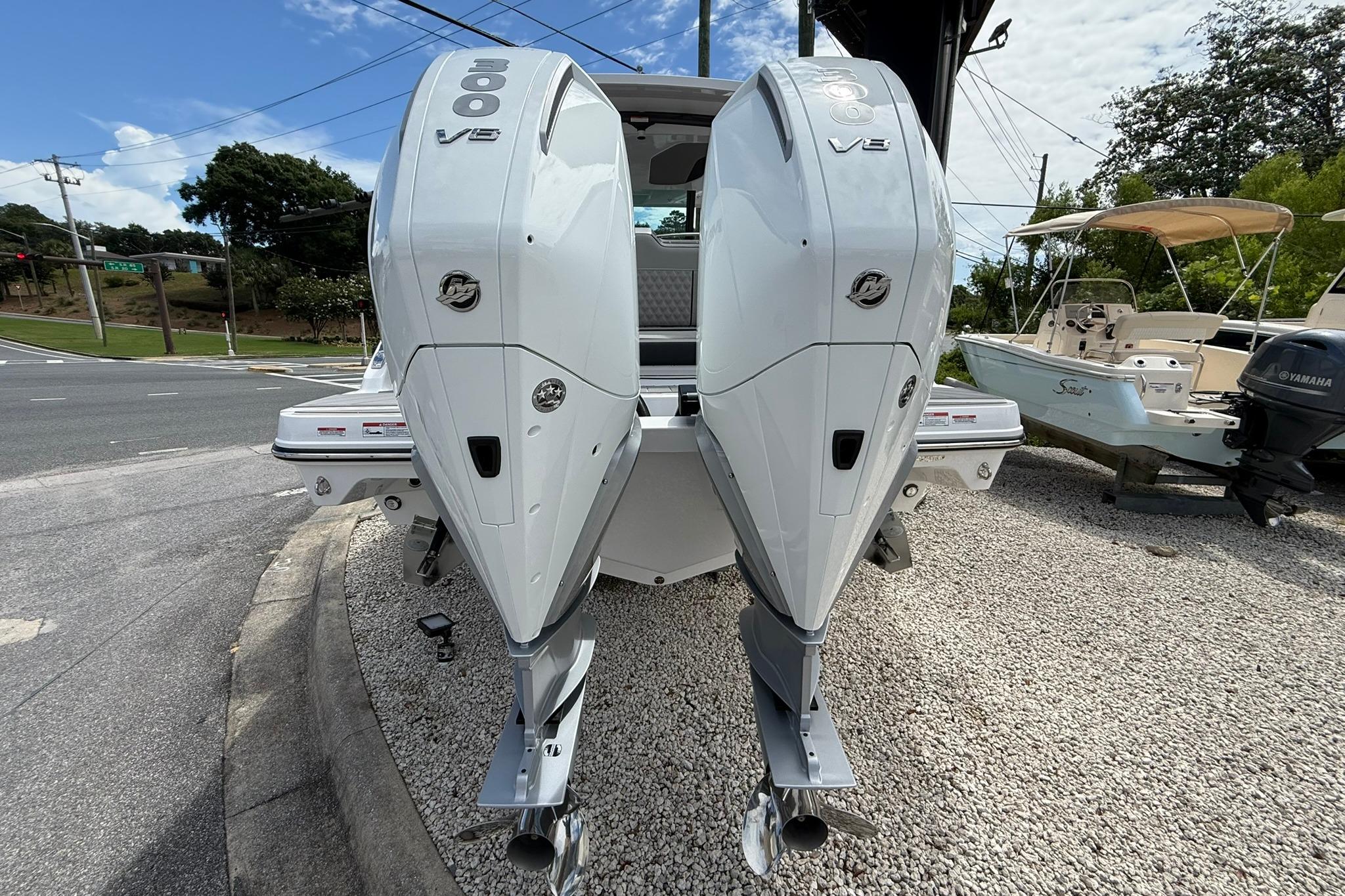 2027 Monterey Elite 30 OB boat with dual V8 outboard engines, parked on gravel.