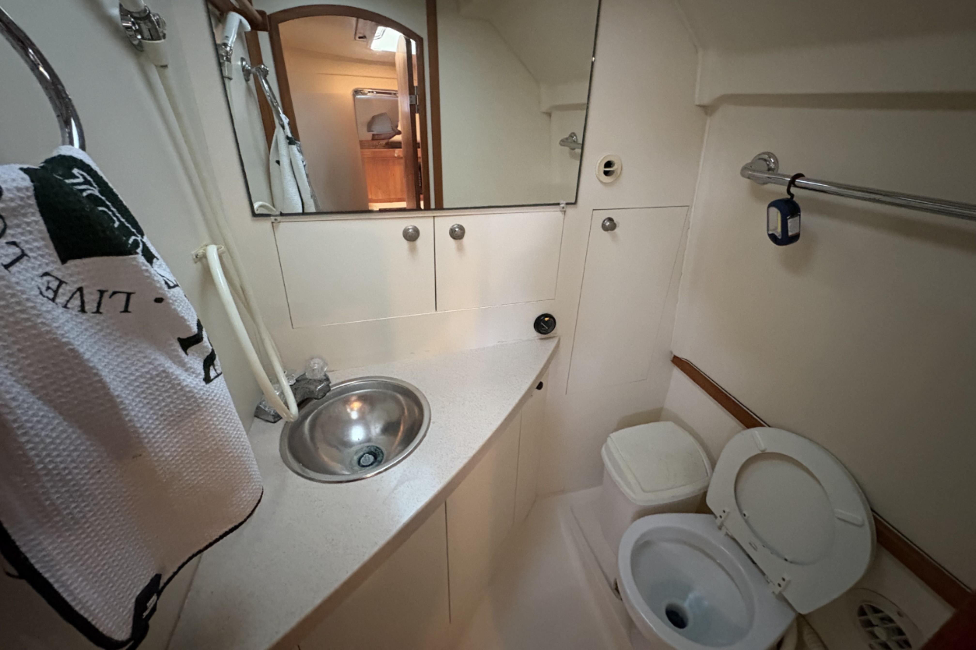 2003 Mainship Pilot 30-II boat bathroom with sink, mirror, and toilet.