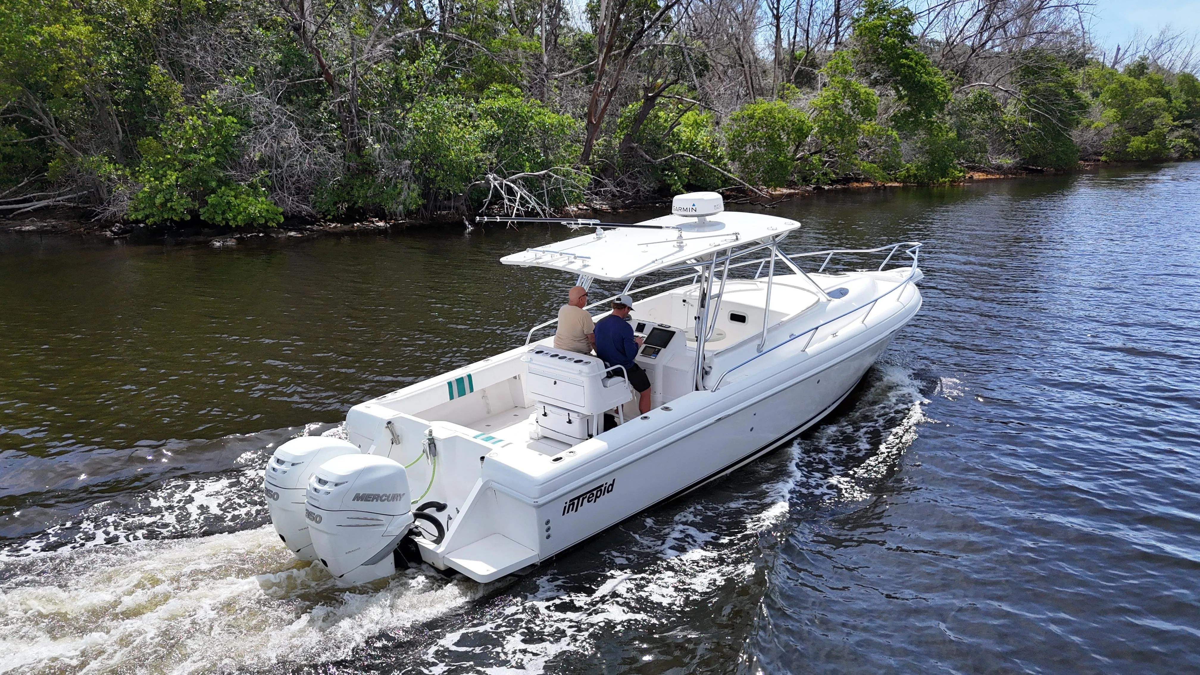 2004 Intrepid 348 WA boat cruising on a river with lush green banks.