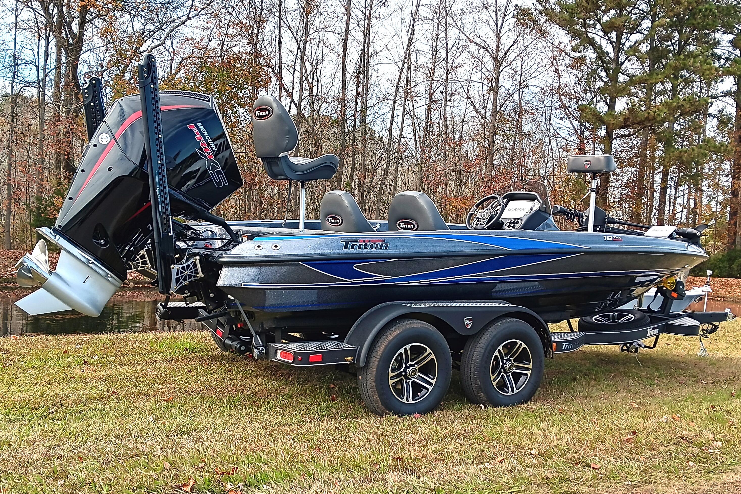 2026 Triton 18 TrX boat on trailer, parked on grass near trees.