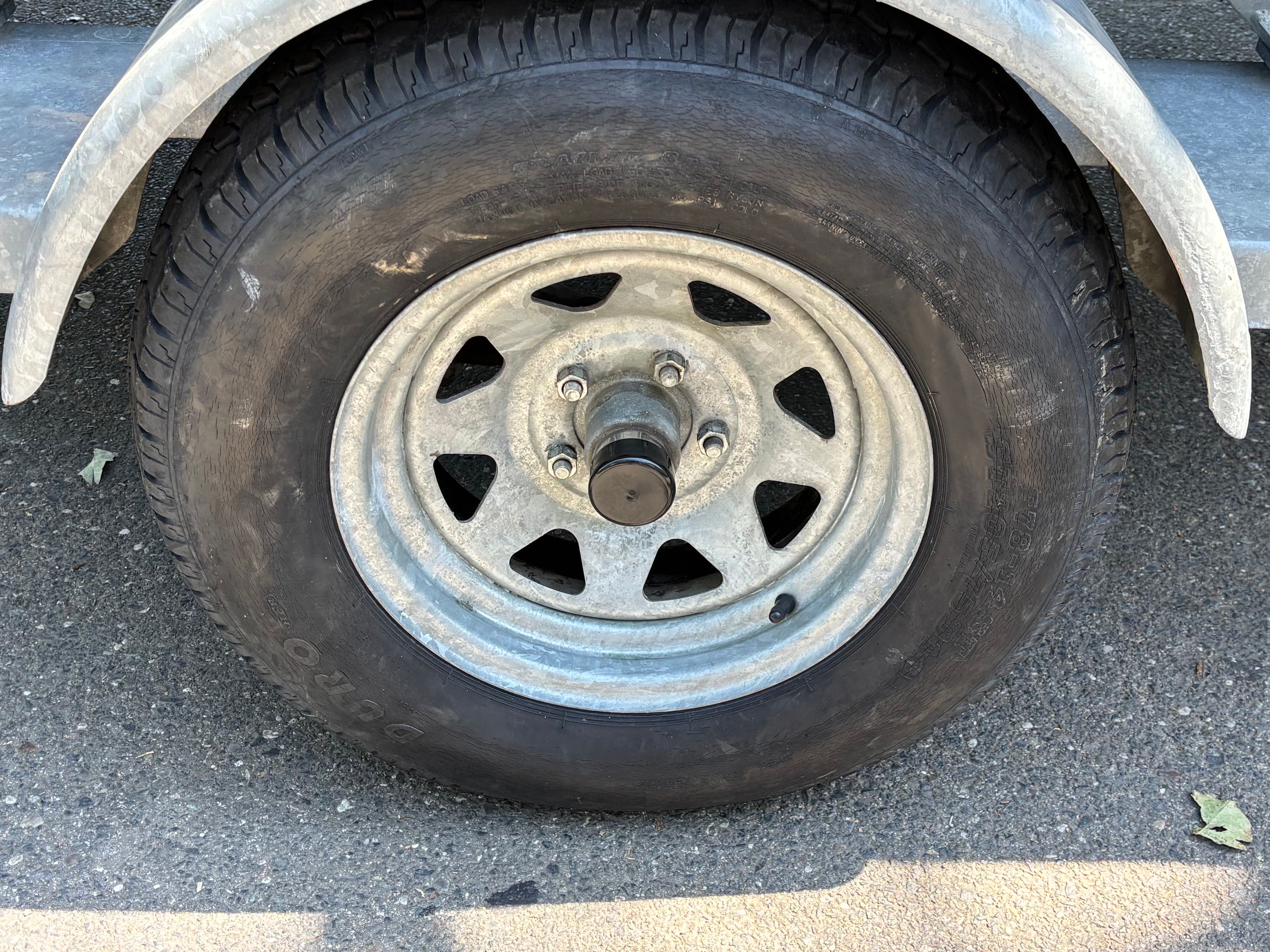 Close-up of a boat trailer wheel on asphalt.