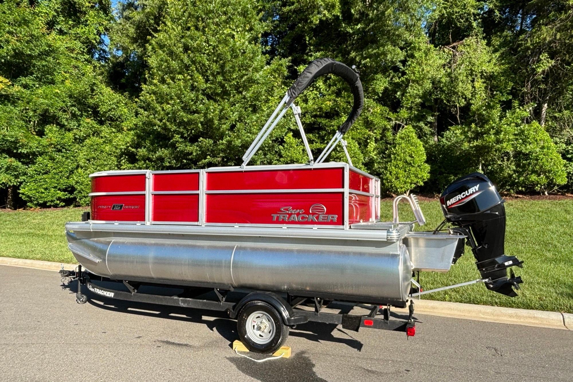 2026 Sun Tracker Party Barge 16 DLX pontoon boat on trailer, parked outdoors.