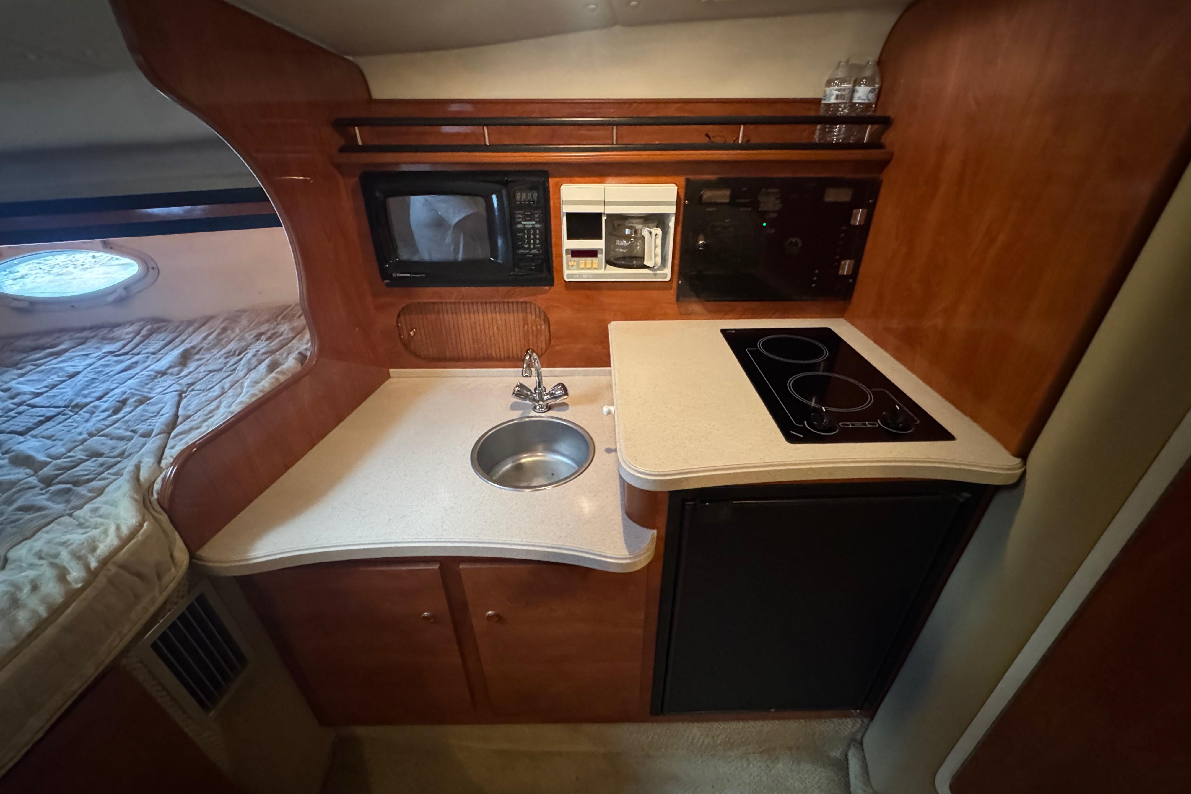 2004 Rinker Fiesta Vee 312 cabin kitchen with sink, stove, and microwave.