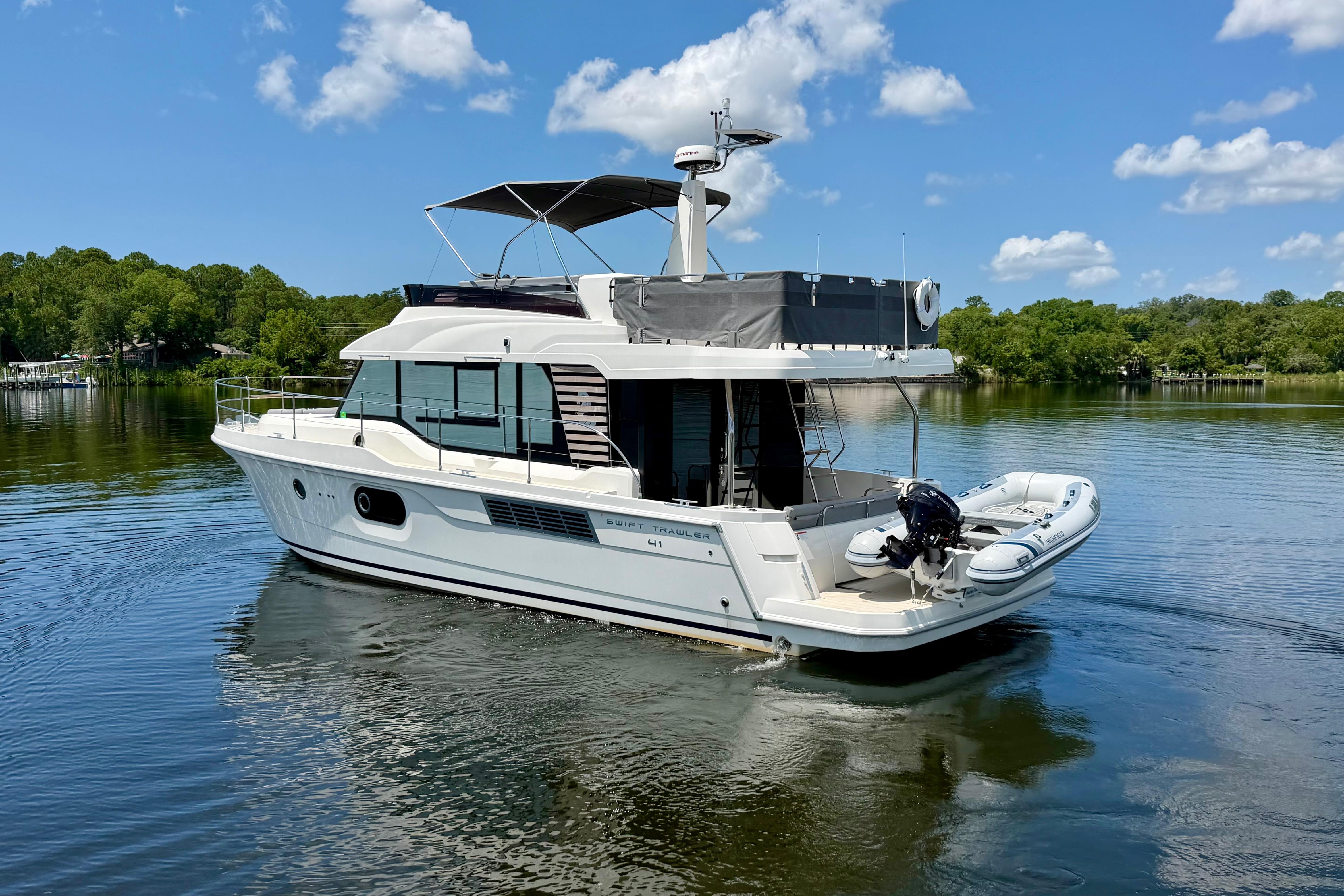 2025 Beneteau Swift Trawler 41 Fly on serene lake under blue sky.