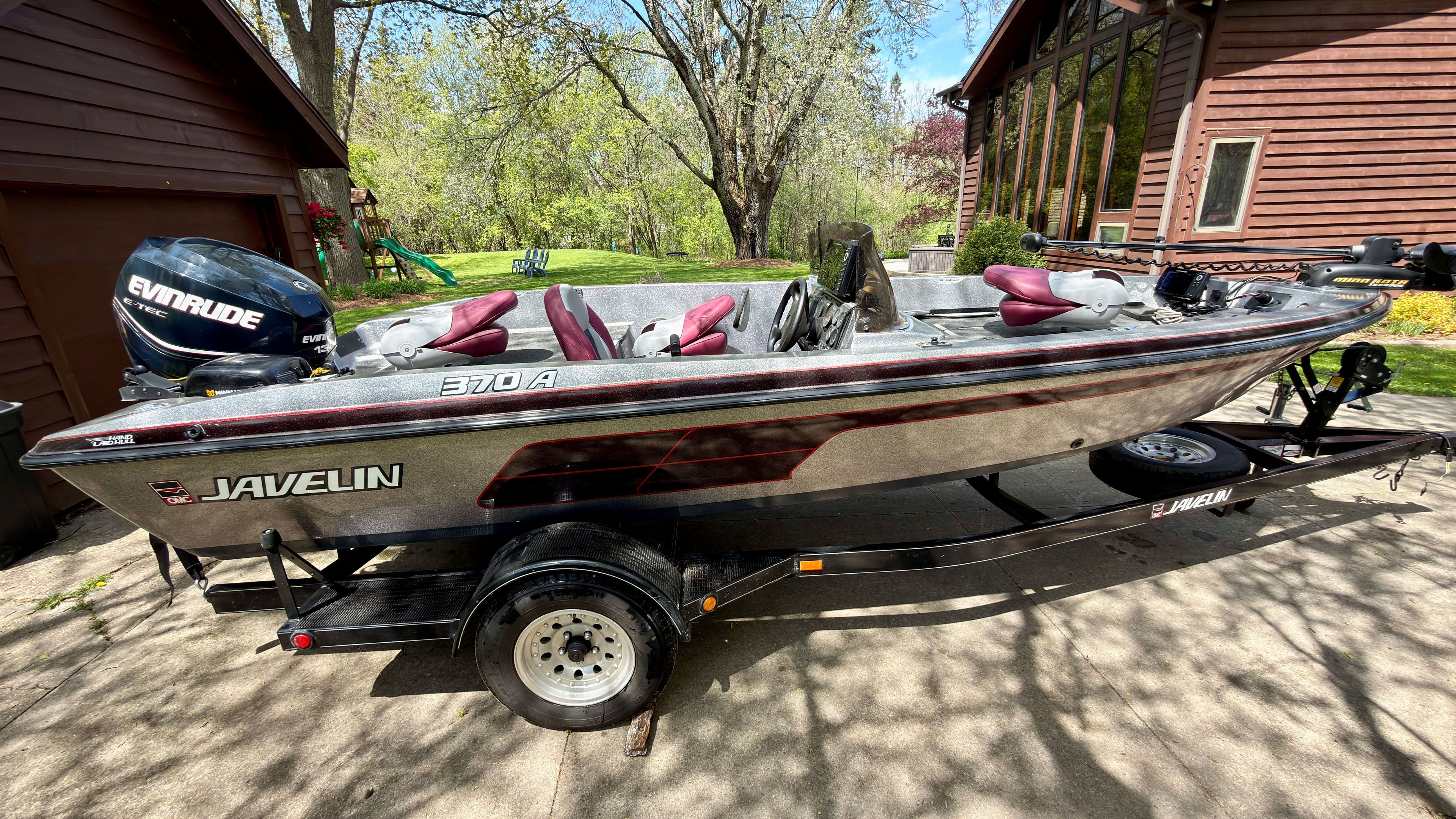 A 1997 Javelin 370A boat on a trailer, parked in front of a house.