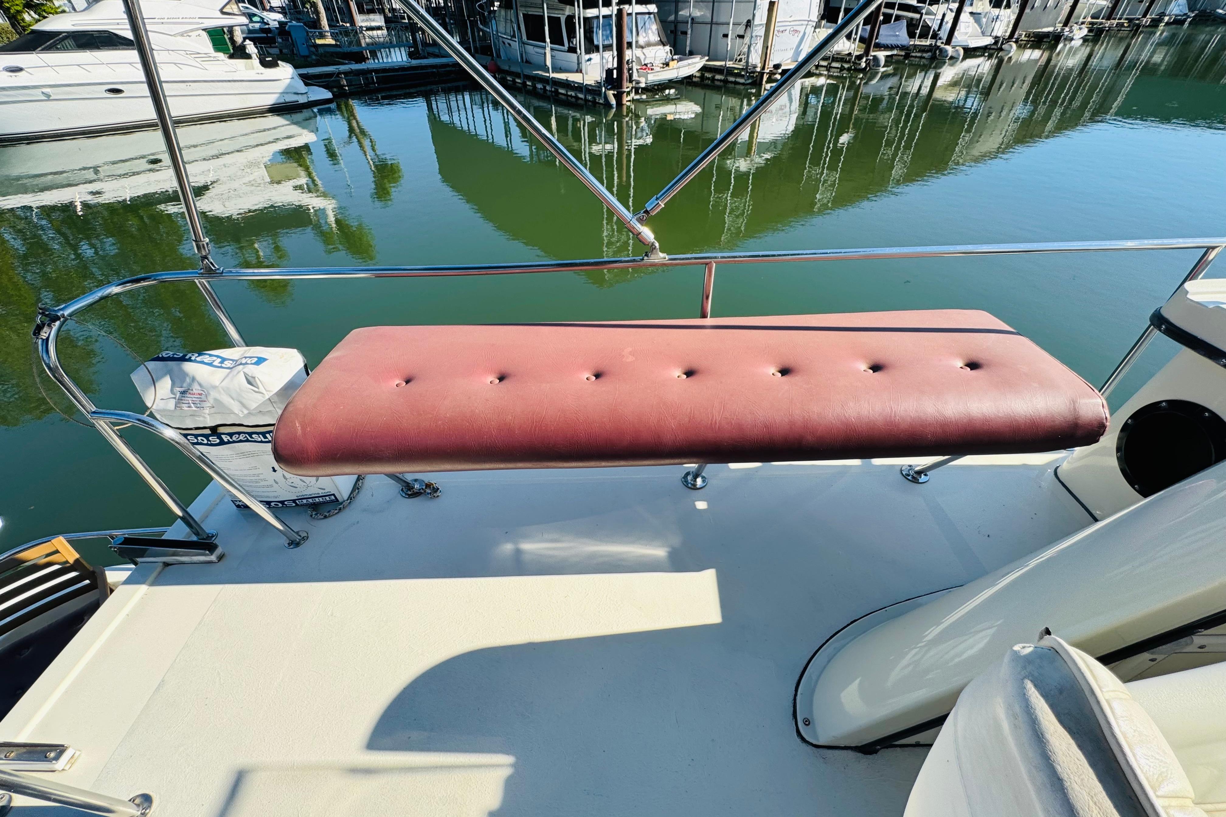 Red cushioned bench on 1996 Nordic Tug 32 boat, docked at marina.