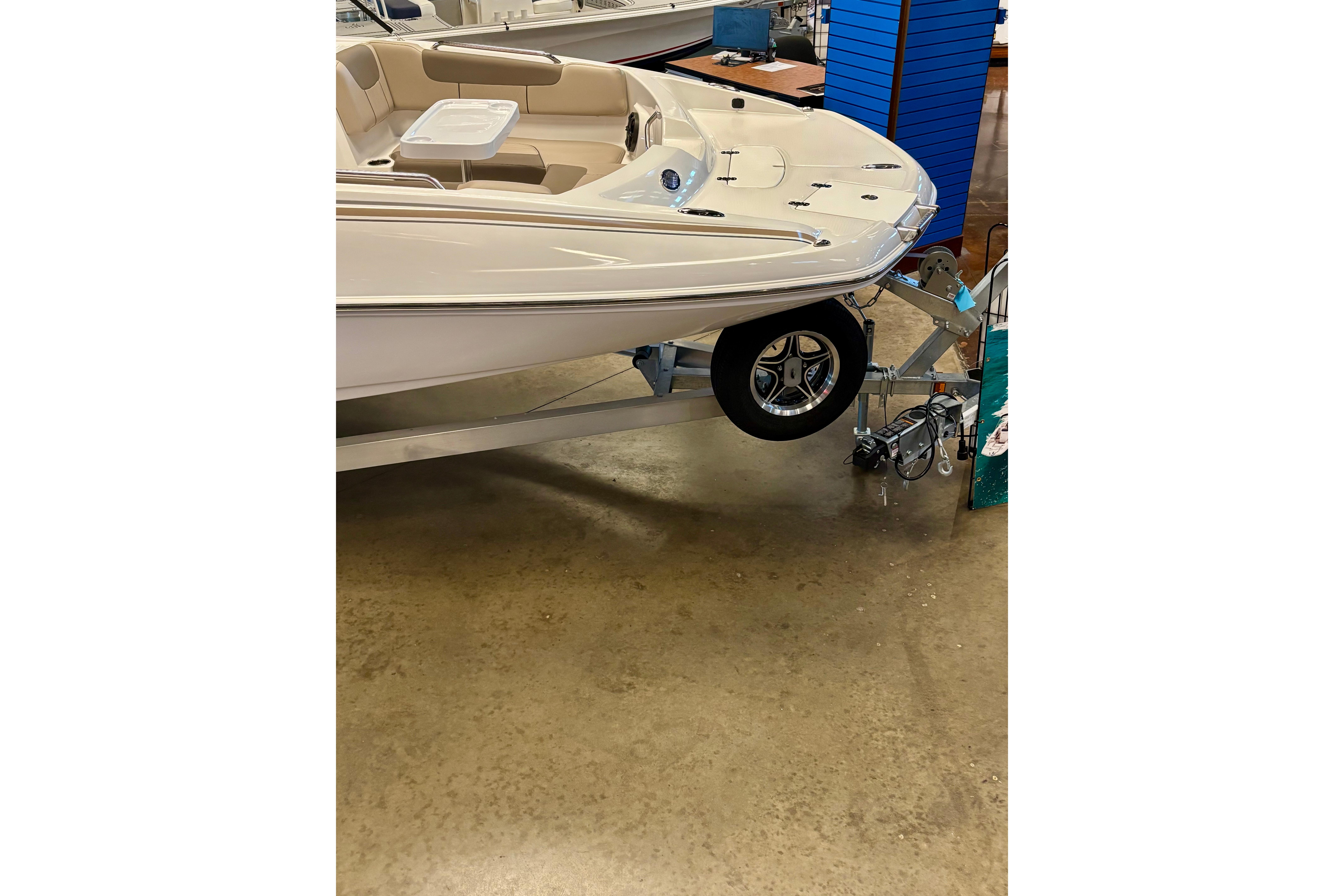 2026 Tahoe 2150 boat on trailer in showroom, featuring beige seating and sleek design.