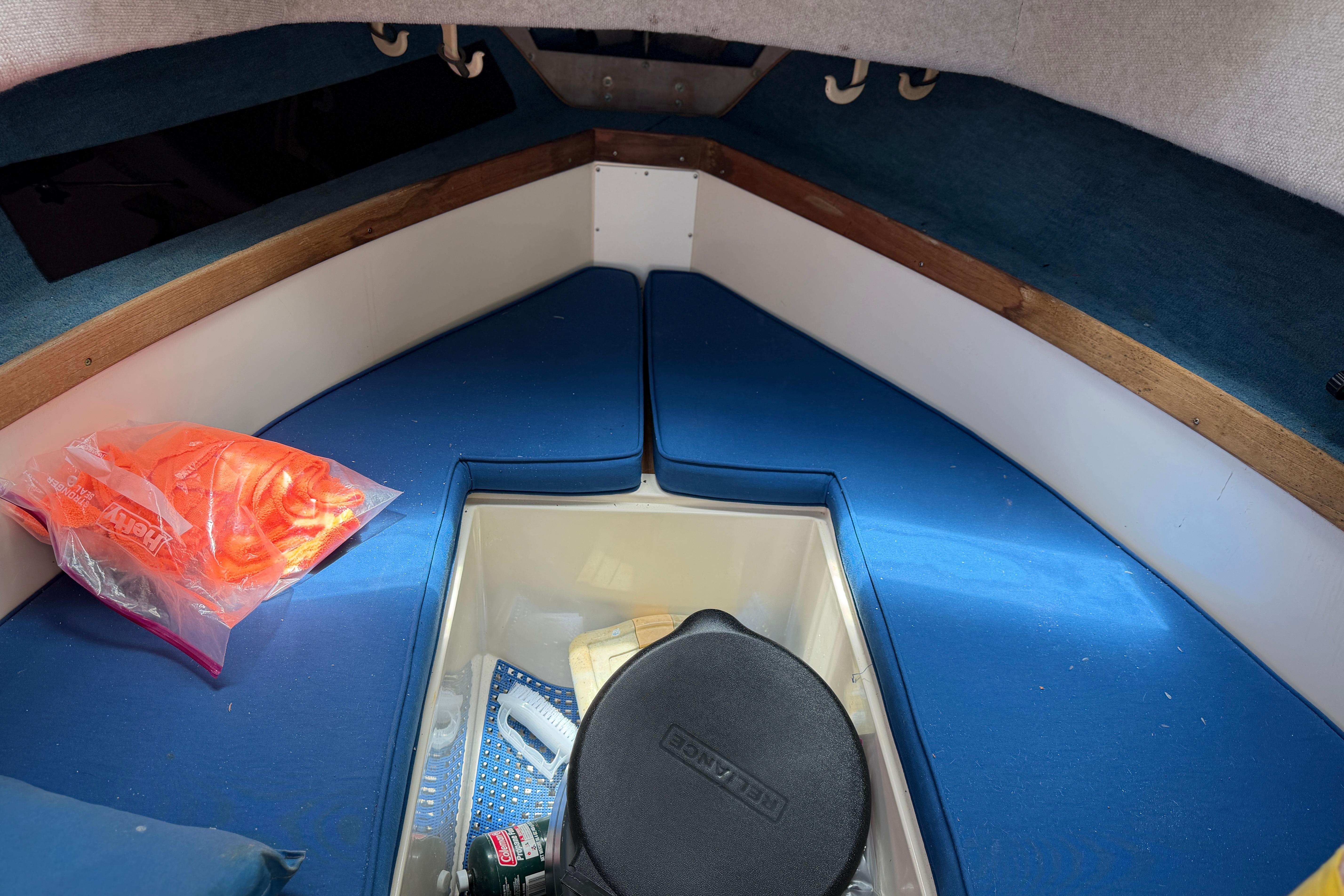 Interior cabin of 1987 Grady-White Seafarer 226 with blue cushions and storage compartment.