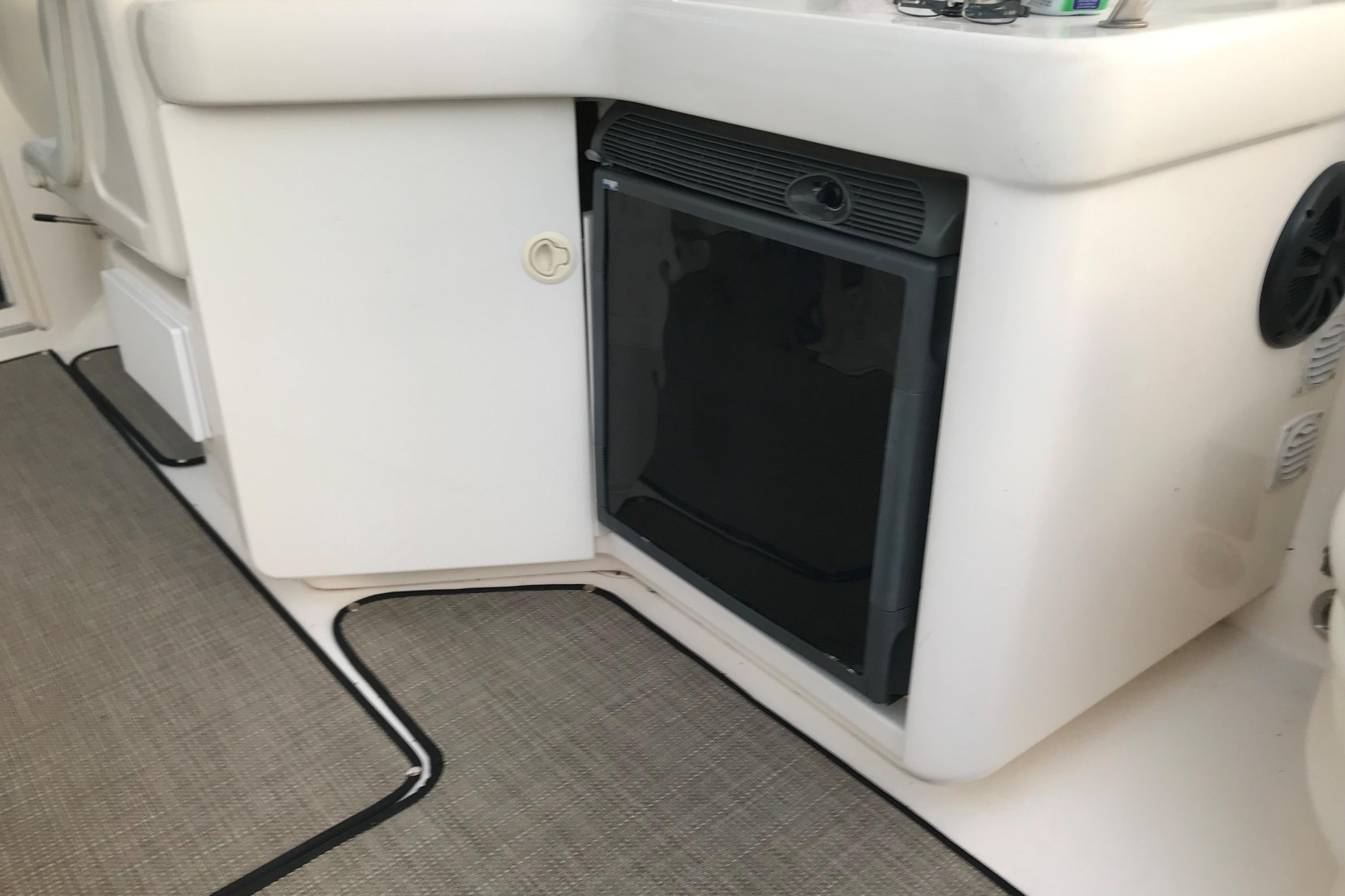 1998 Sea Ray 280 Sun Sport interior with compact refrigerator and carpeted flooring.