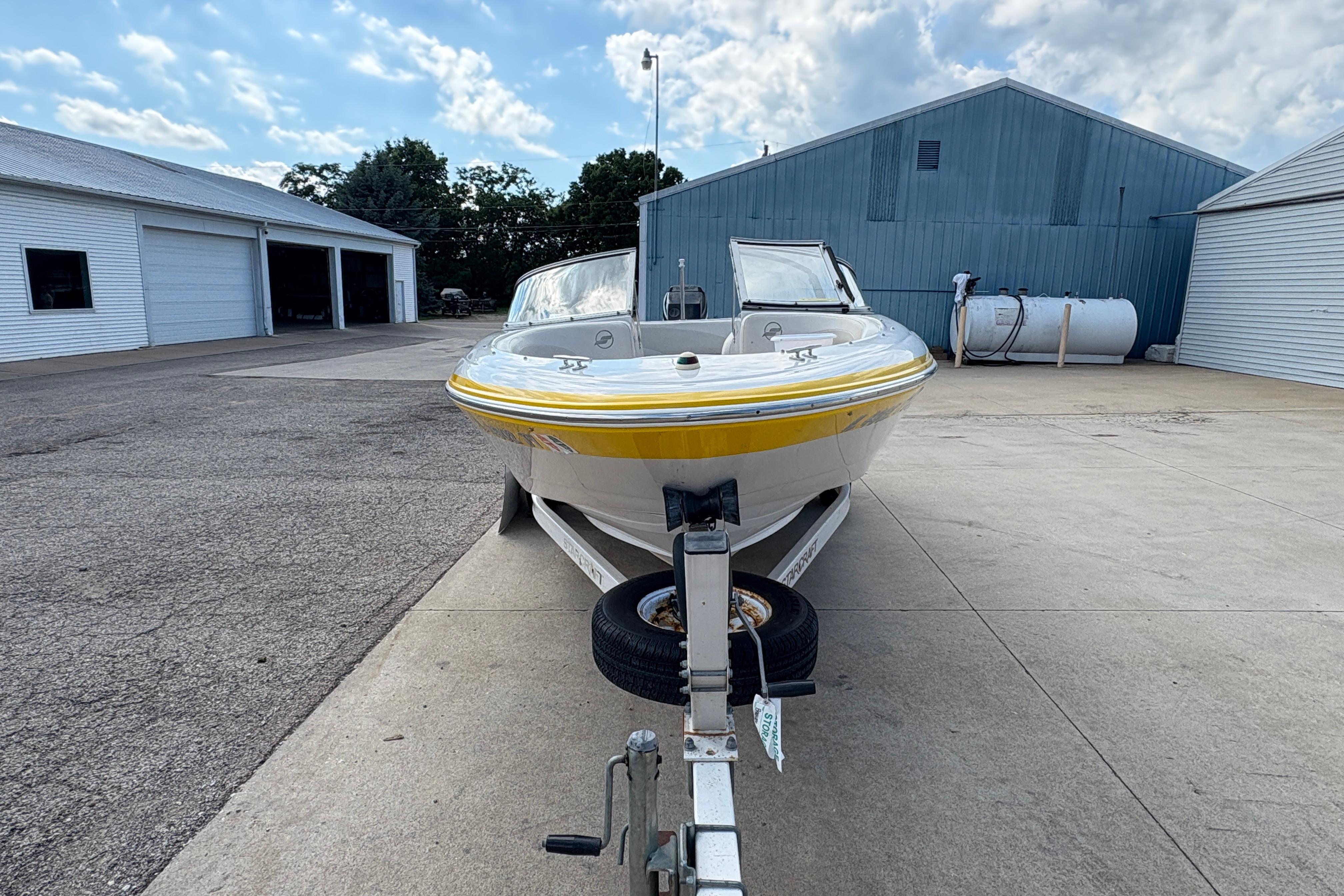 2005 Starcraft C-Star 1700 OB boat on trailer, parked outside industrial buildings.