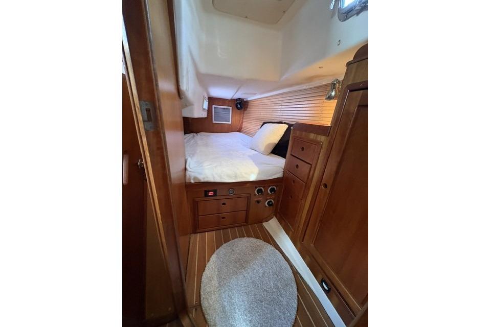 Cozy cabin interior of 2002 Saga 43 yacht with wooden furnishings and bed.