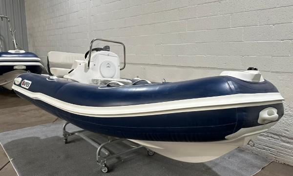 2024 Apex A-13 Deluxe Tender, blue and white inflatable boat in showroom.