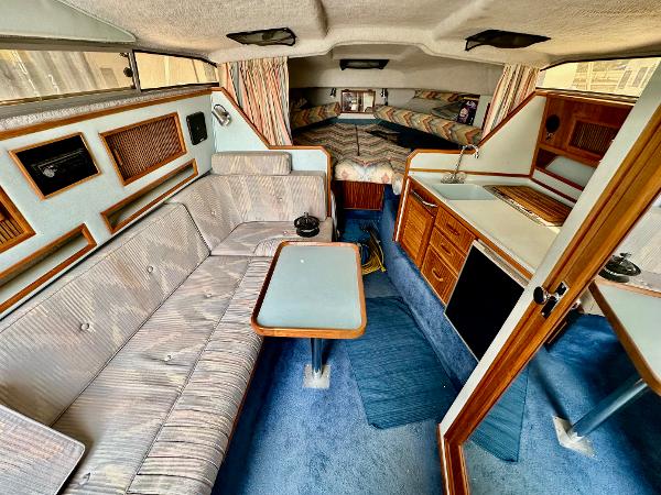 Interior of a 1987 Sea Ray 270 Sundancer boat with seating, table, and kitchenette.