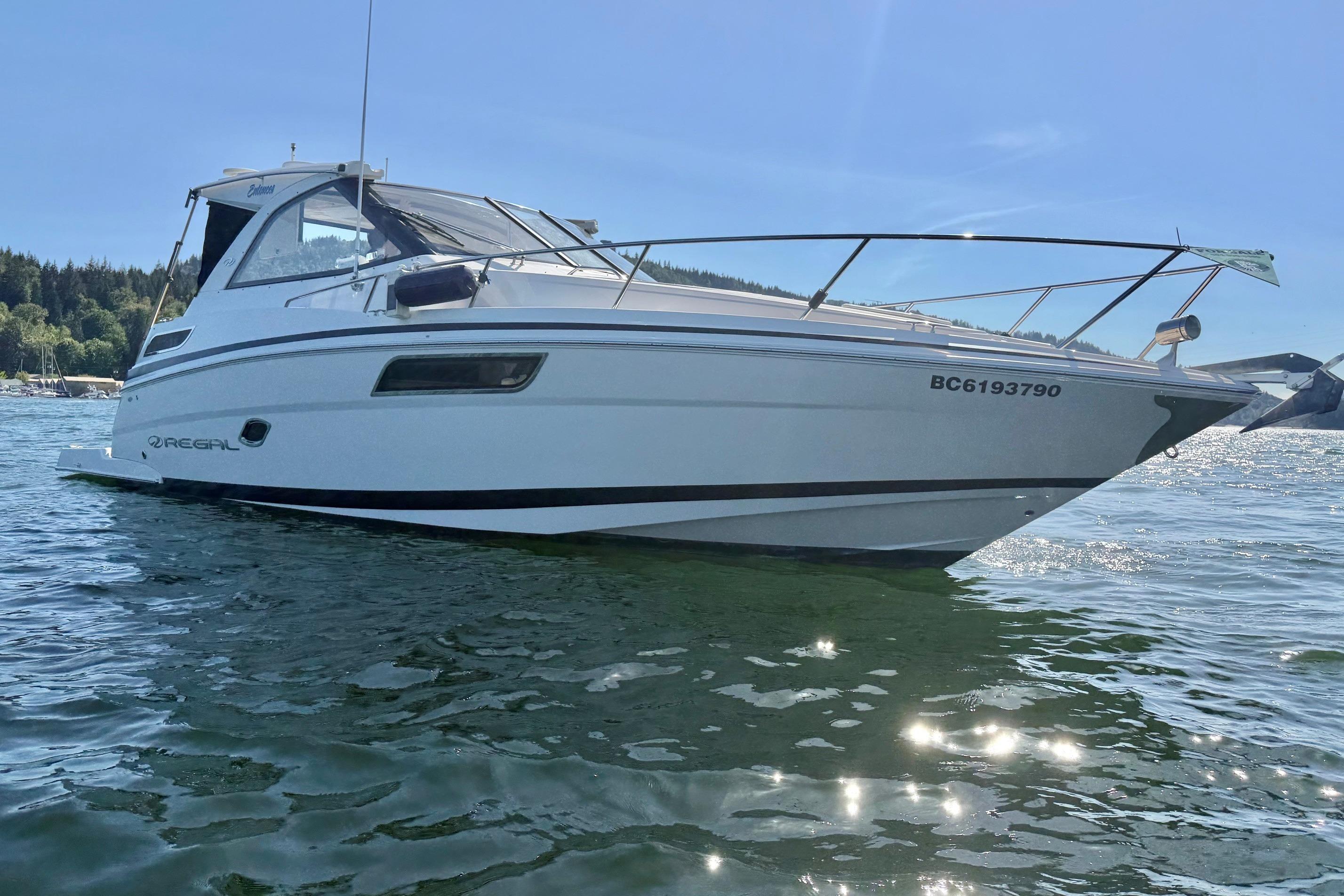 2013 Regal 35 Sport Coupe boat on water, sunny day, forested shoreline in background.