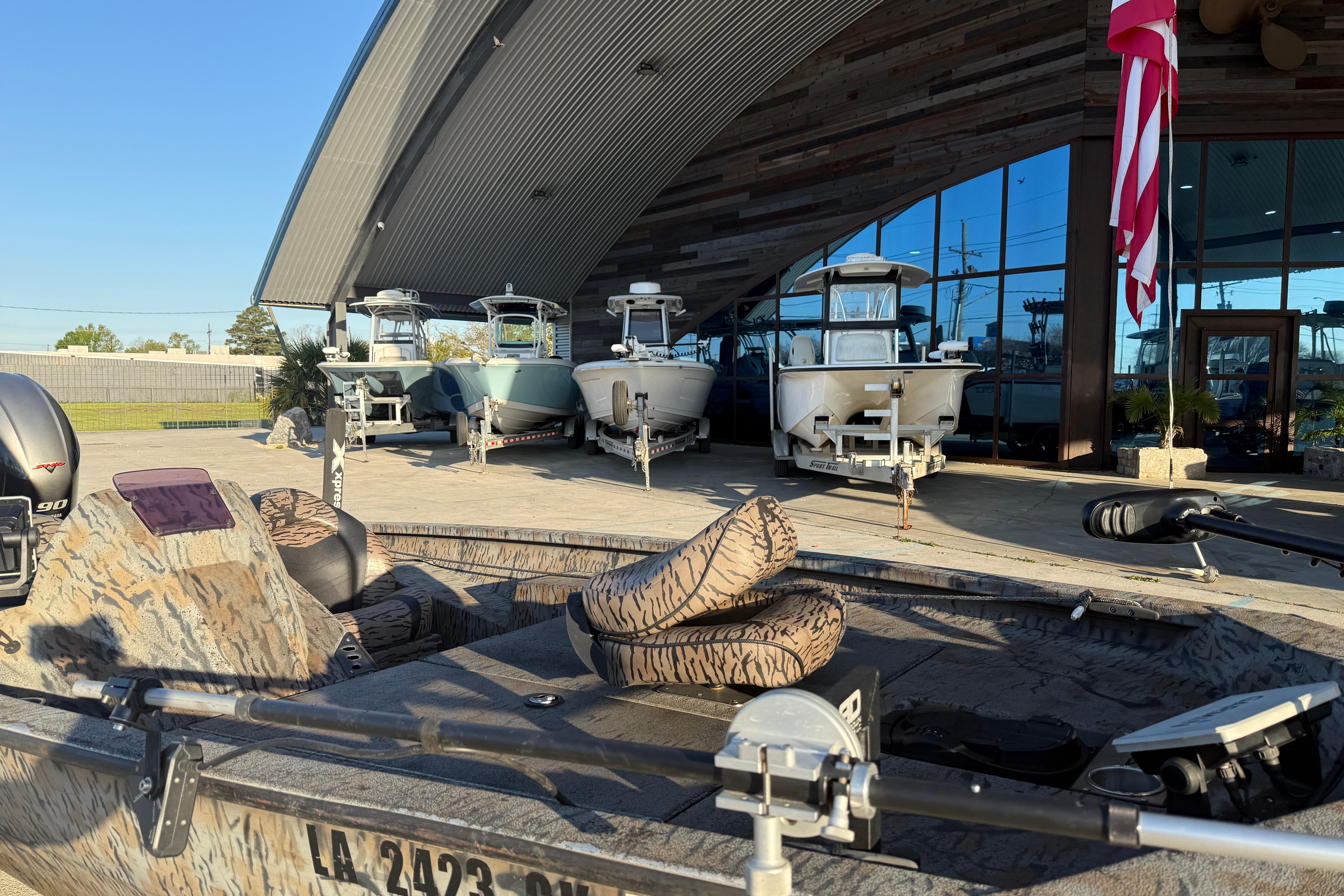 2019 Xpress XP7 boat displayed outside showroom with other boats and American flag.