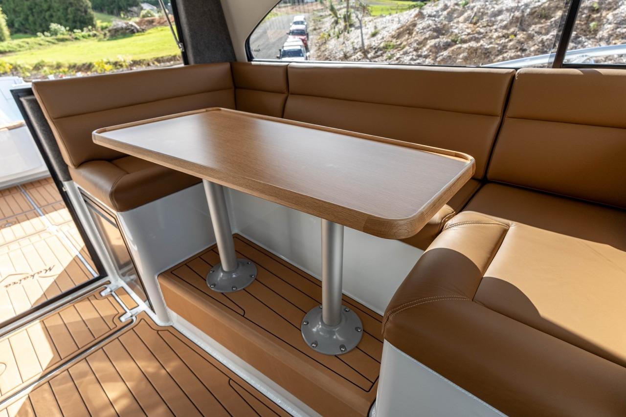 Luxurious interior of 2025 Makaira Gen 3 36 yacht with brown seating and wooden table.