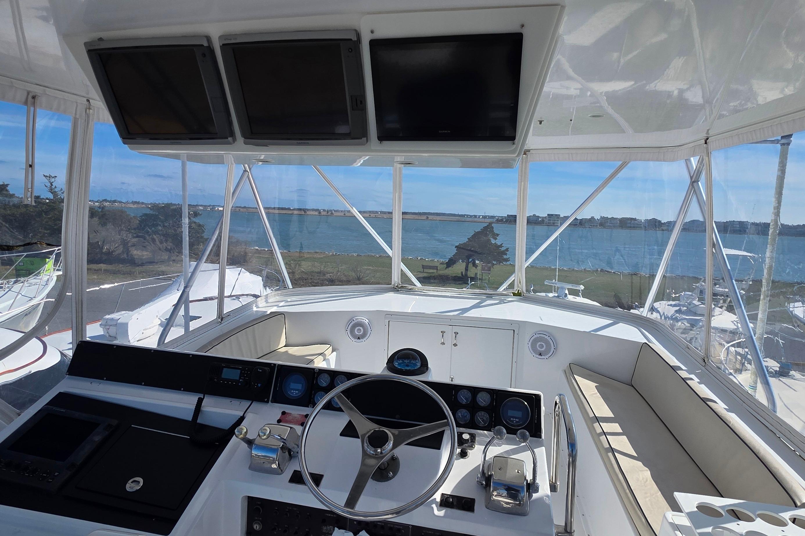 Cockpit view of 1989 Hatteras 52 Convertible yacht overlooking serene waterfront.