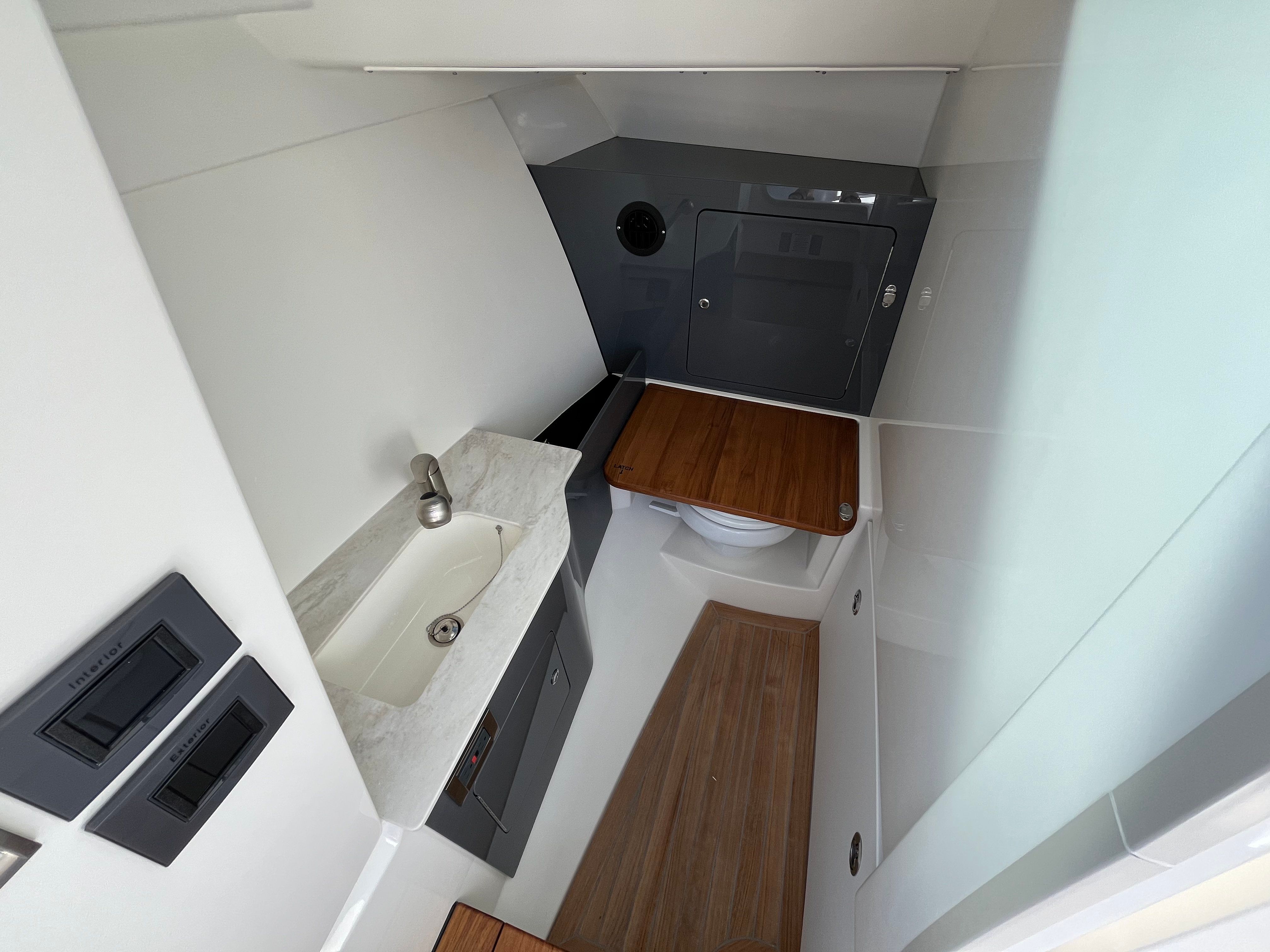 Interior of a modern boat cabin with a sink, toilet, and wood accents.