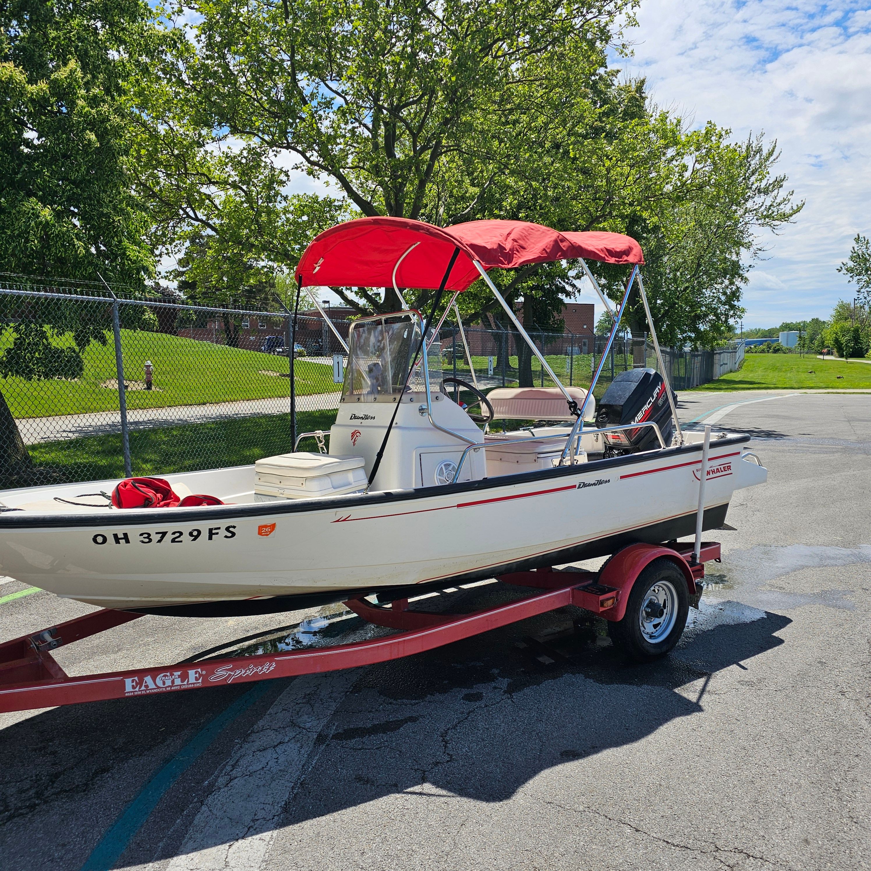 A Boston Whaler Dauntless 15 boat on a trailer with a red sunshade.