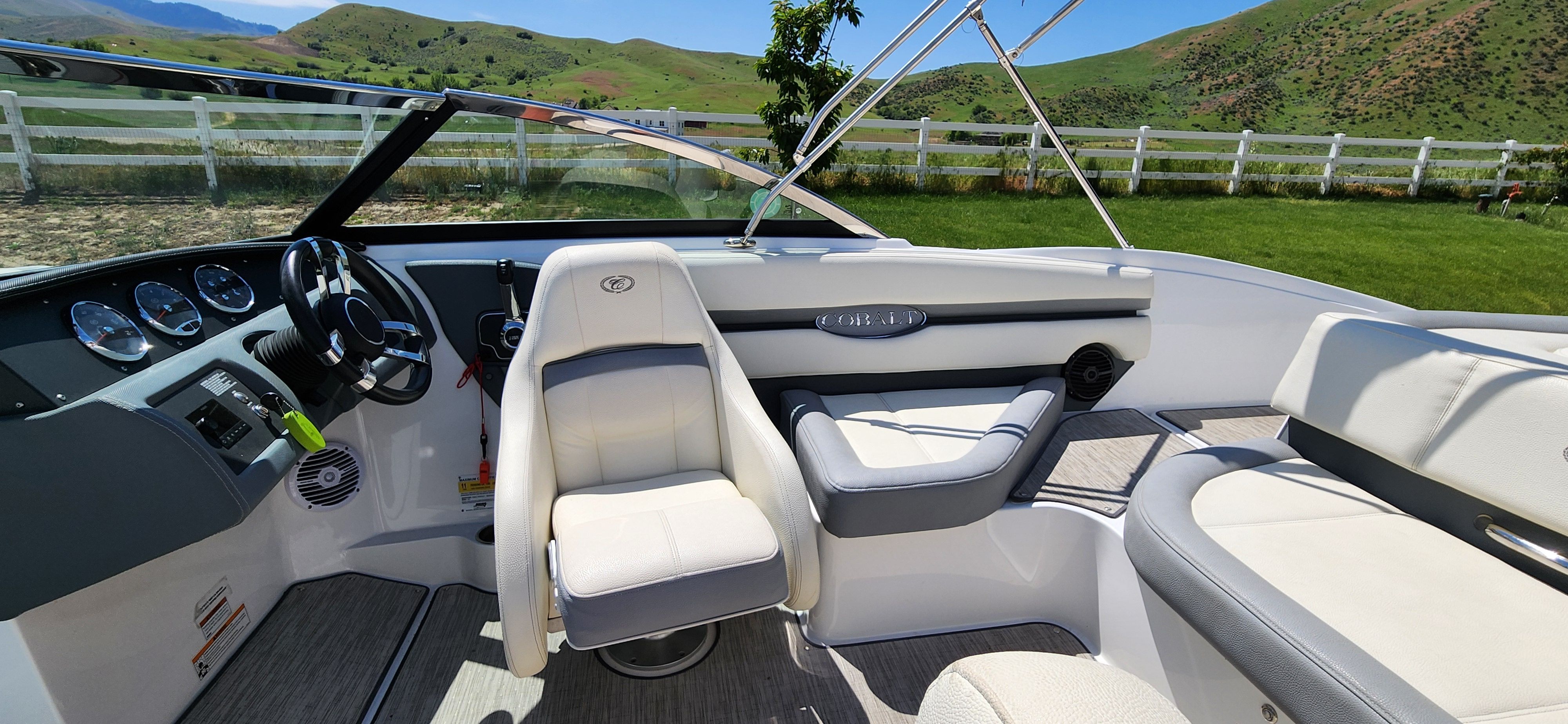 Interior of a Cobalt CS22 boat with white seats and green hills in the background.