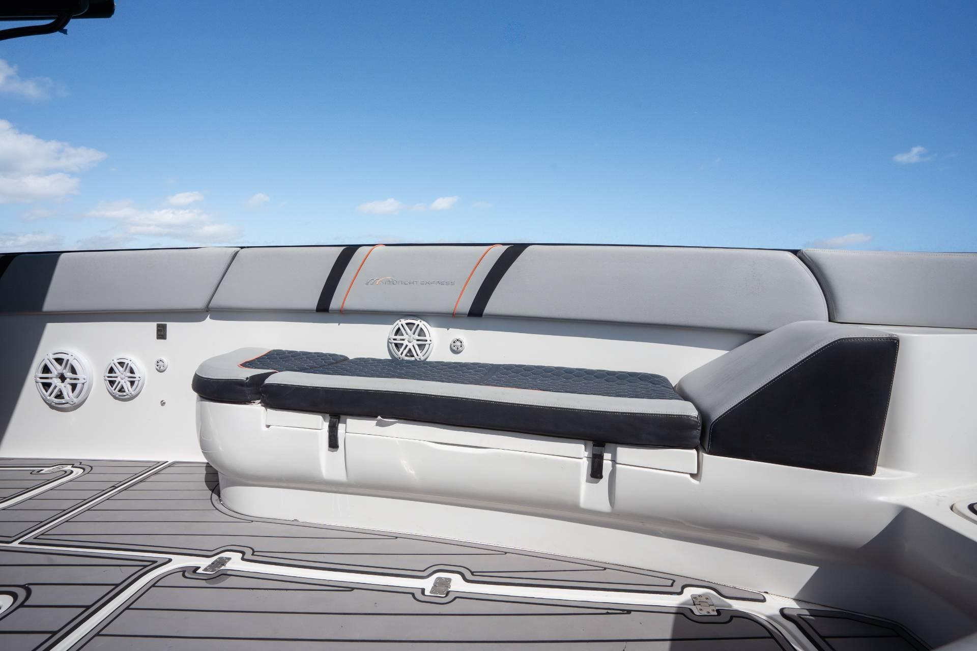 2014 Midnight Express 37 Open boat interior with cushioned seating and speakers under a clear sky.