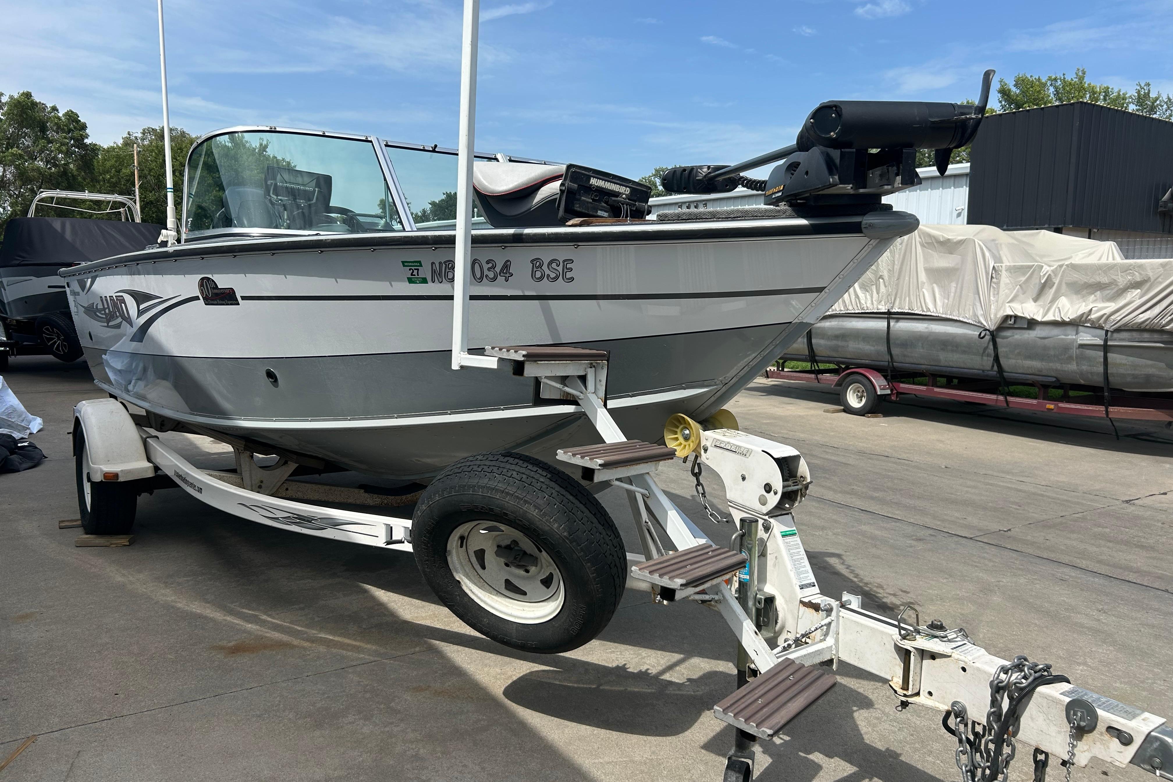 2008 Lund 1850 Fisherman boat on trailer, parked outdoors under clear sky.