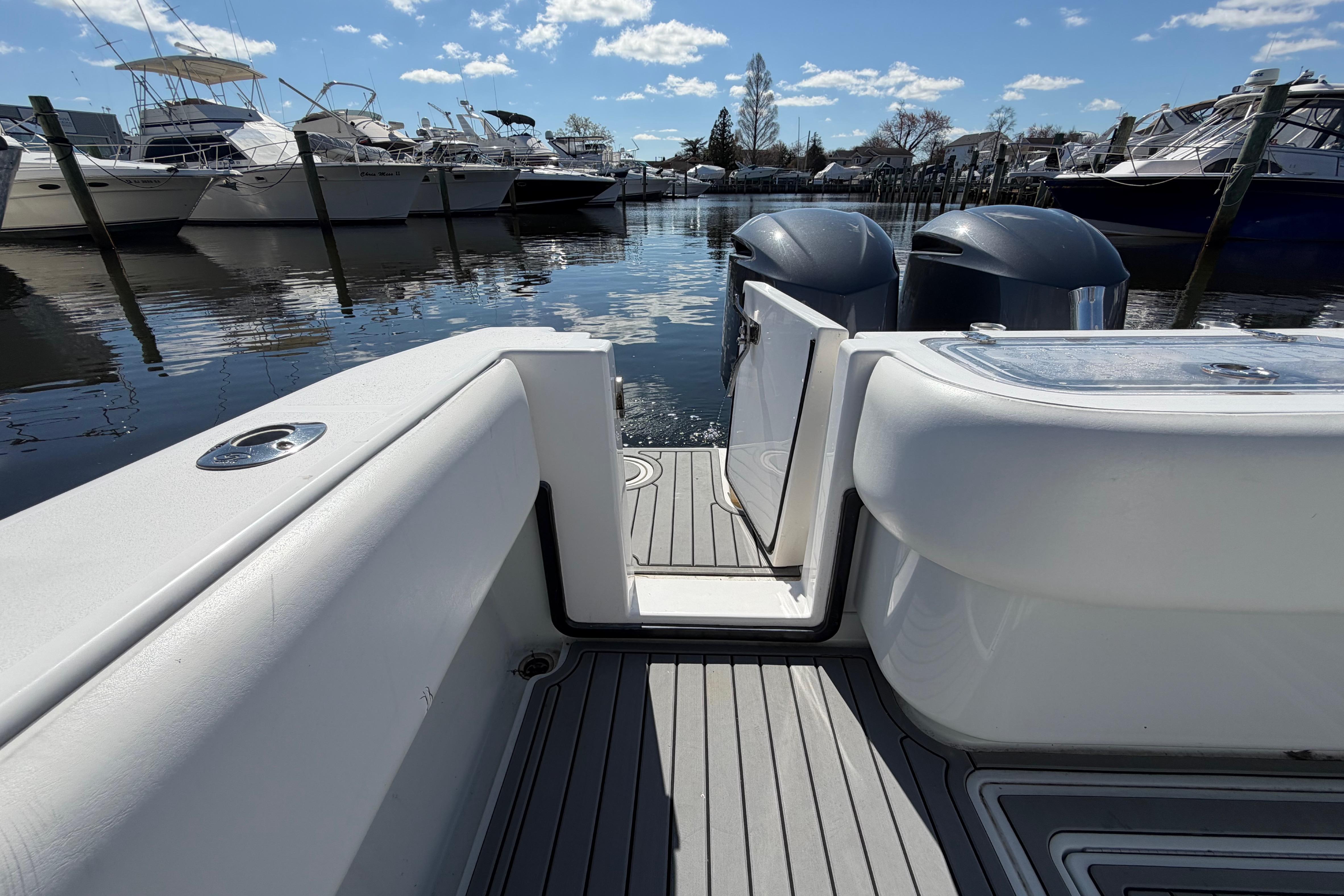 2015 Contender 32 ST boat with dual engines docked at a marina under a clear sky.