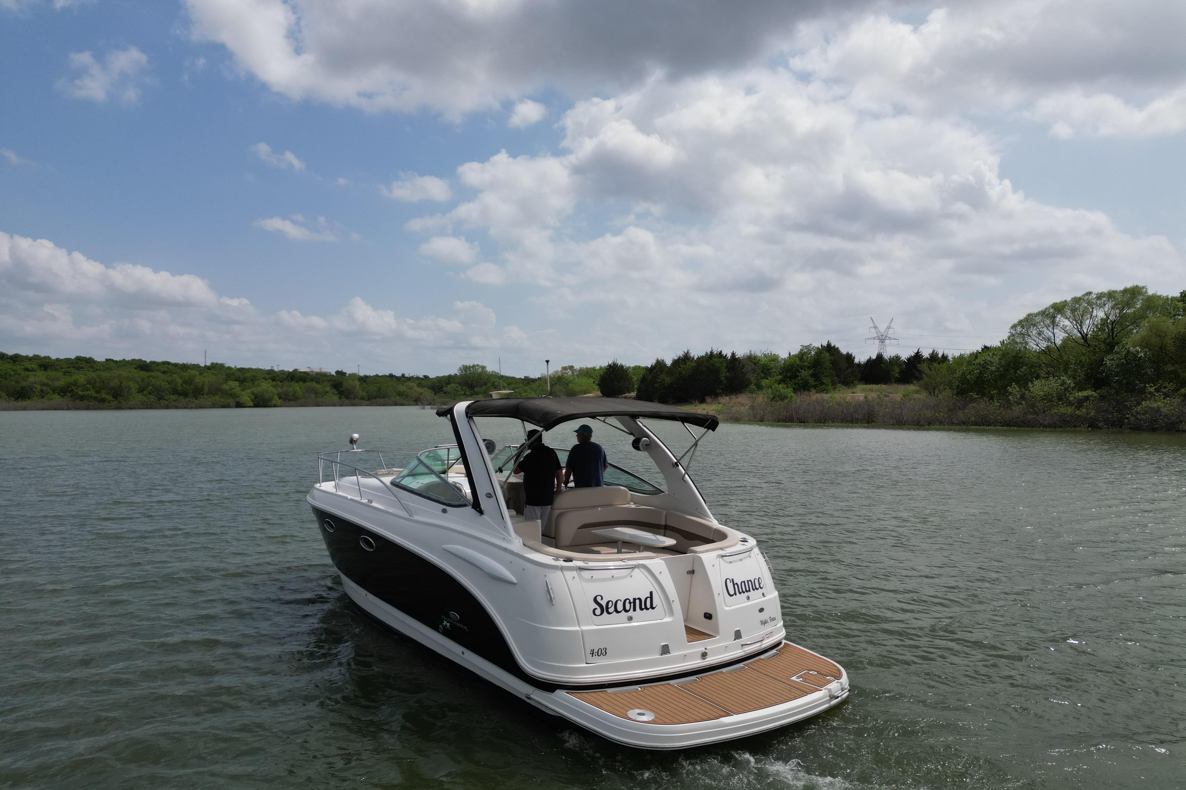 2006 Chaparral 330 Signature boat cruising on a scenic lake under a cloudy sky.