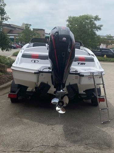 2025 Tahoe T21 boat with outboard motor and ladder, parked outdoors.