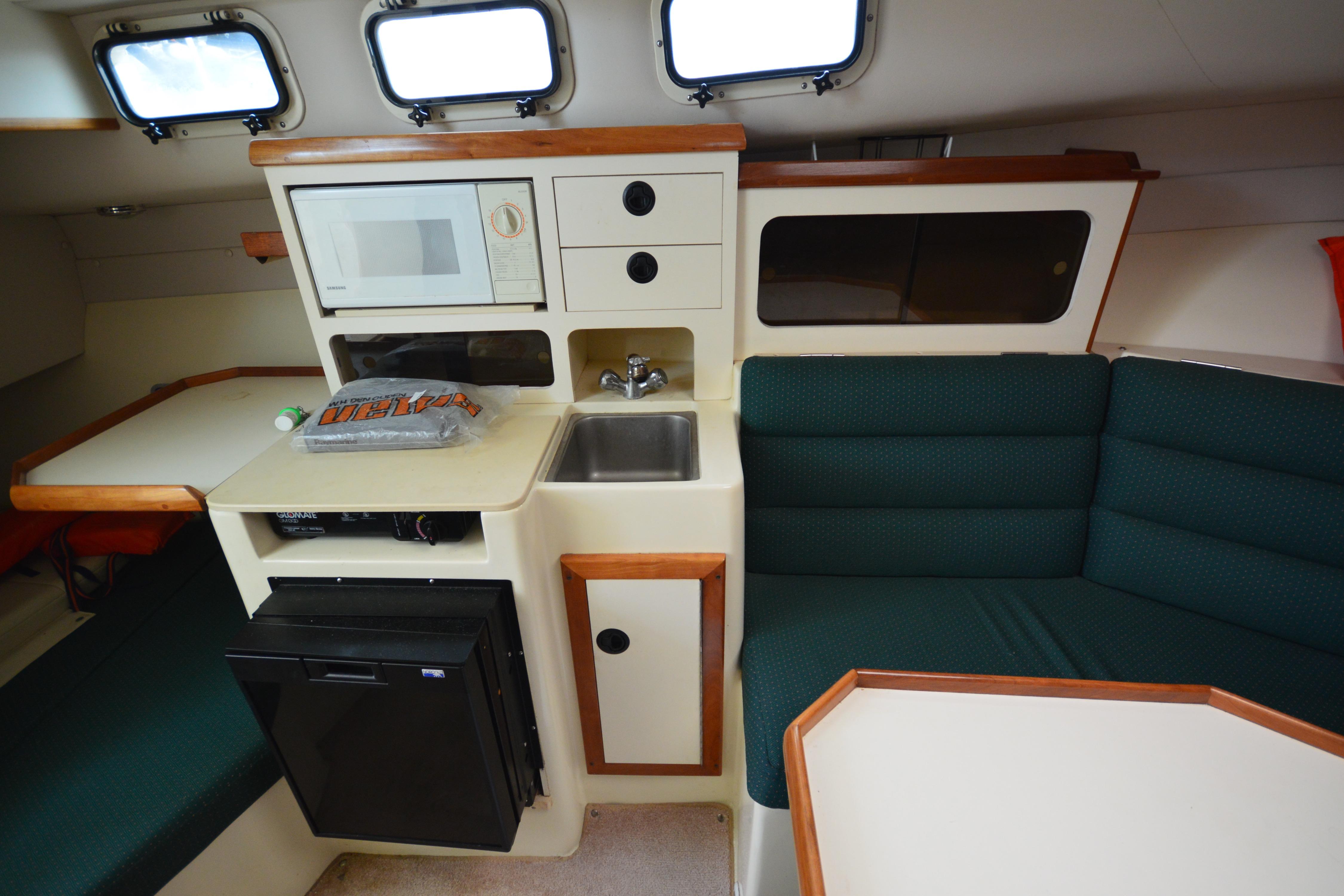 2001 Albin 28 Tournament Express interior with kitchenette, microwave, sink, and seating area.