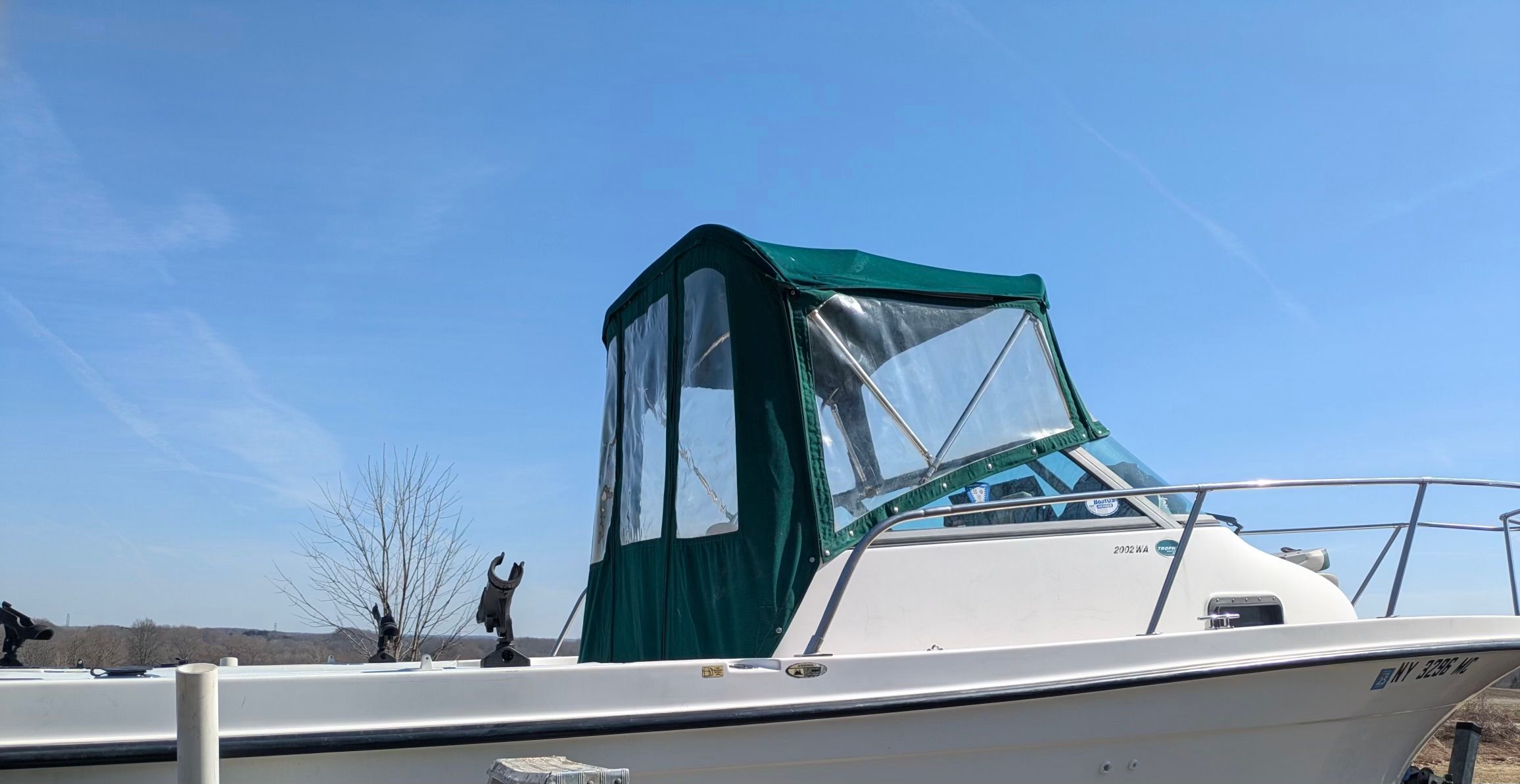 2005 Bayliner Trophy boat with green canopy, blue sky.