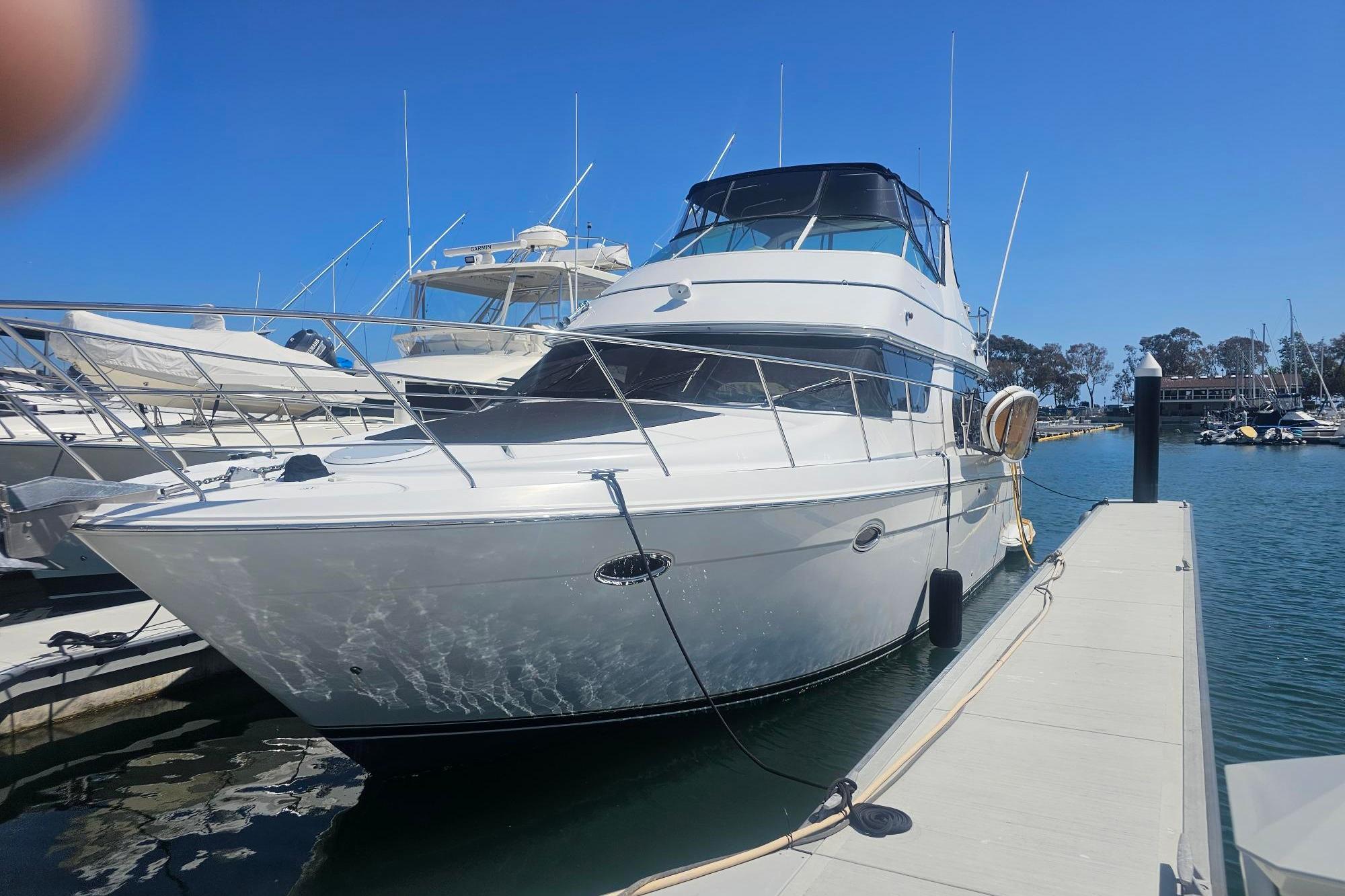 2002 Carver 450 Voyager Pilothouse yacht docked at marina under clear blue sky.