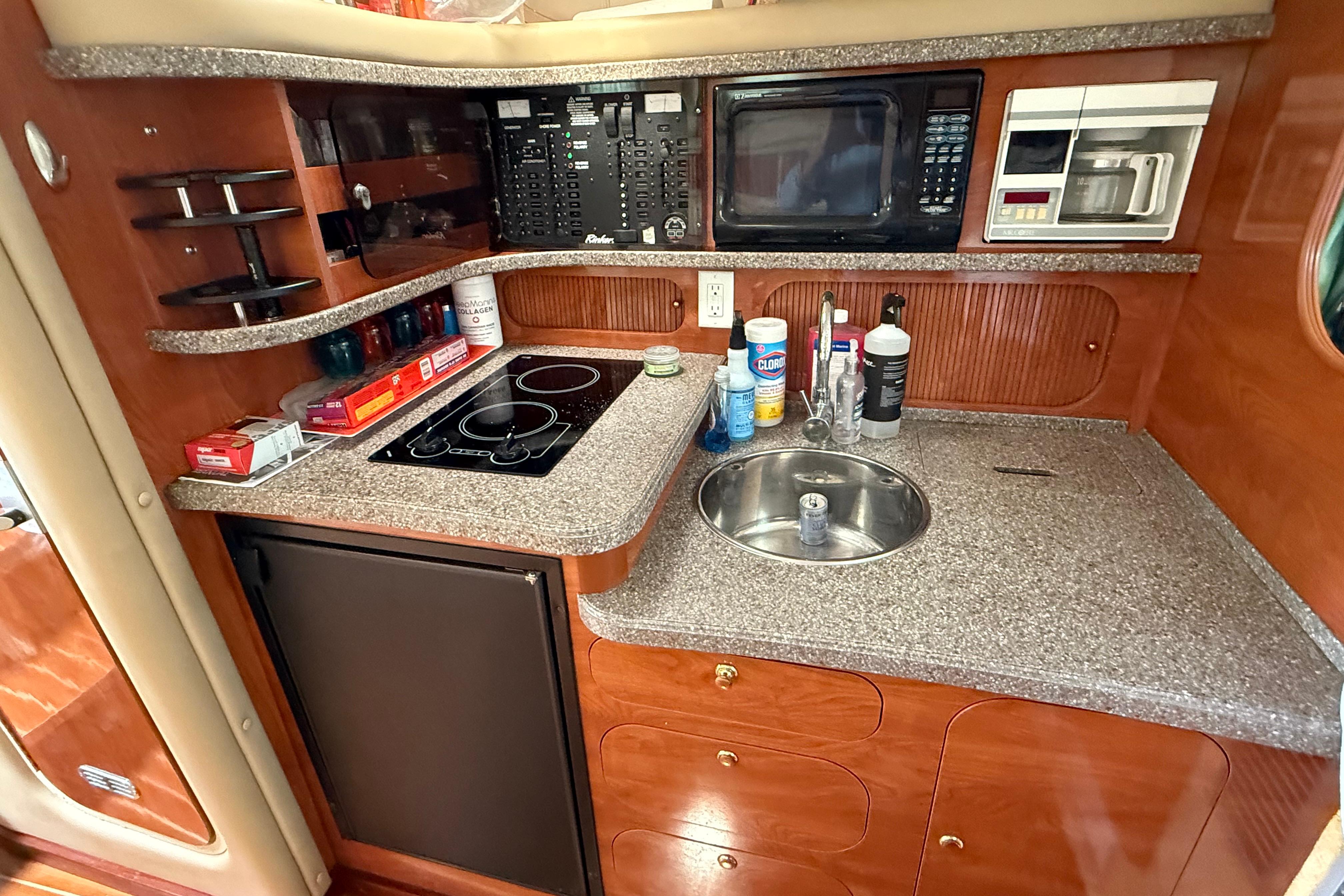 2004 Rinker 342 yacht kitchen with stove, sink, microwave, and storage cabinets.
