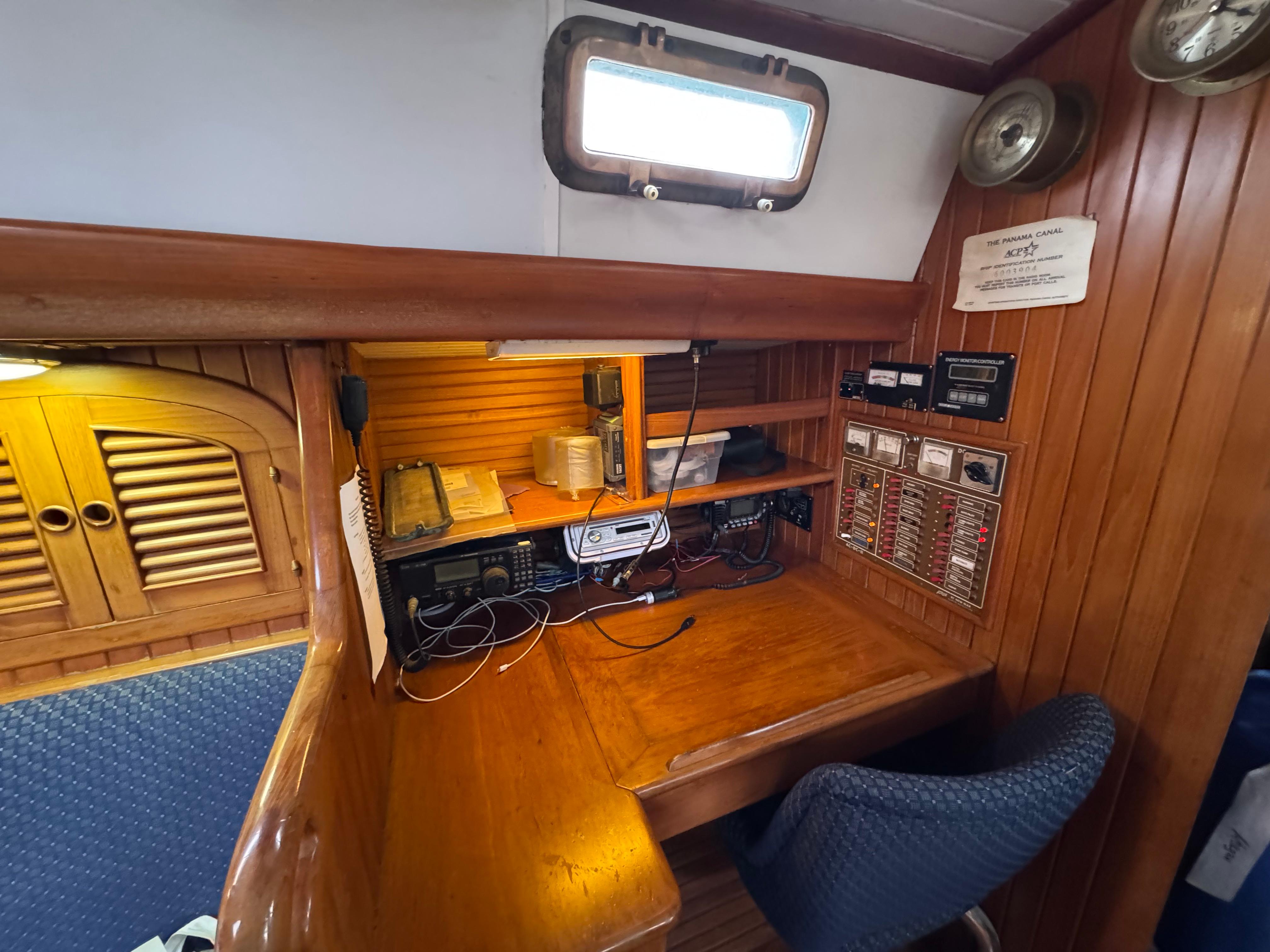 Navigation station on a 1982 Passport 40 sailboat with wooden interior and communication equipment.