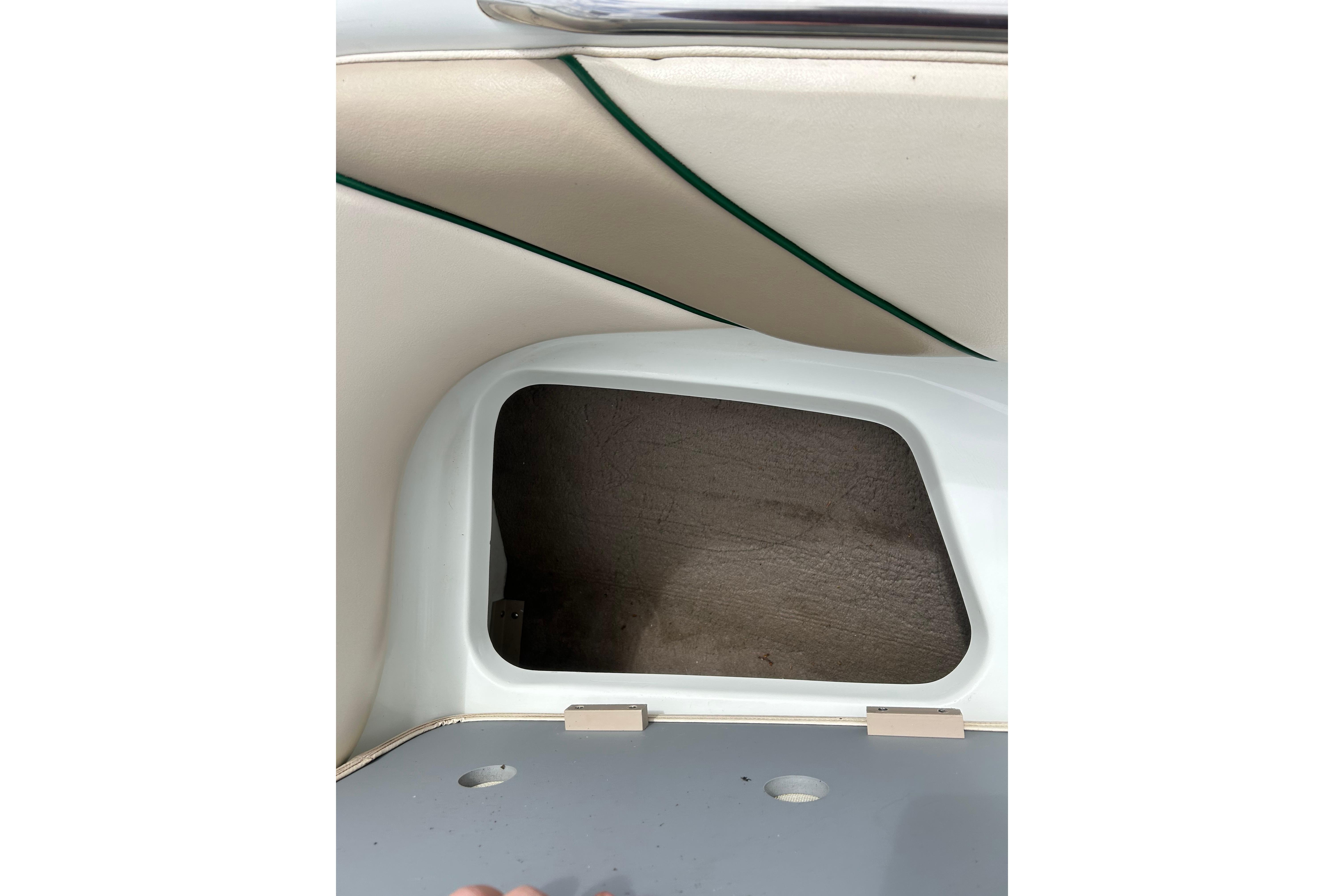 Storage compartment in a 2000 Starcraft 1810 boat, featuring beige and green interior.