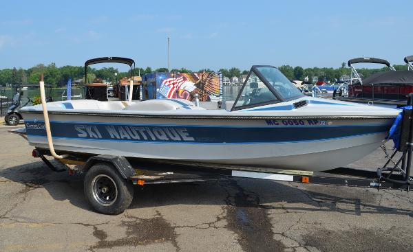 1989 Correct Craft Ski Nautique boat on trailer, blue and white design, parked outdoors.