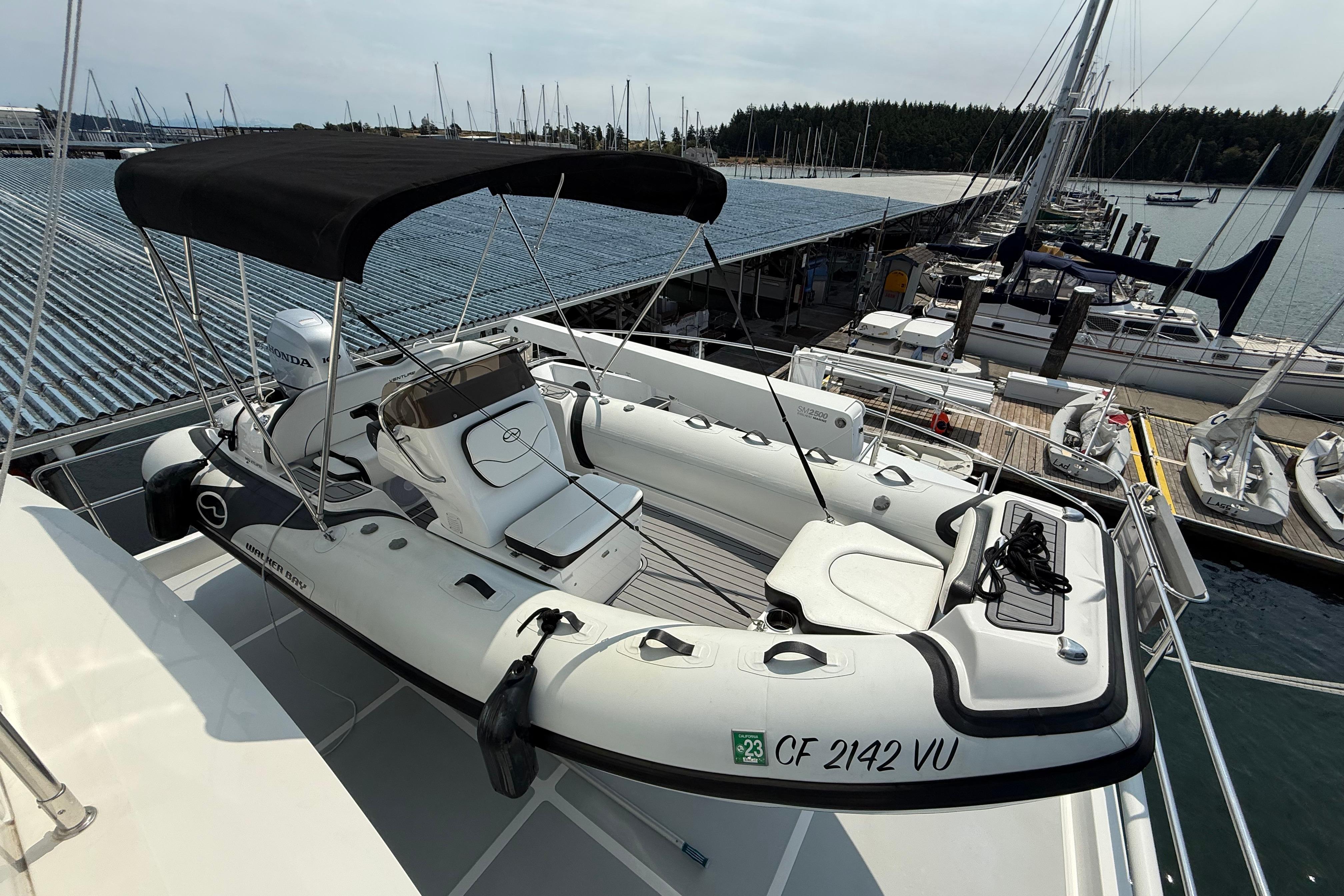2009 Nordhavn N64 yacht with a small boat on deck, docked at a marina.