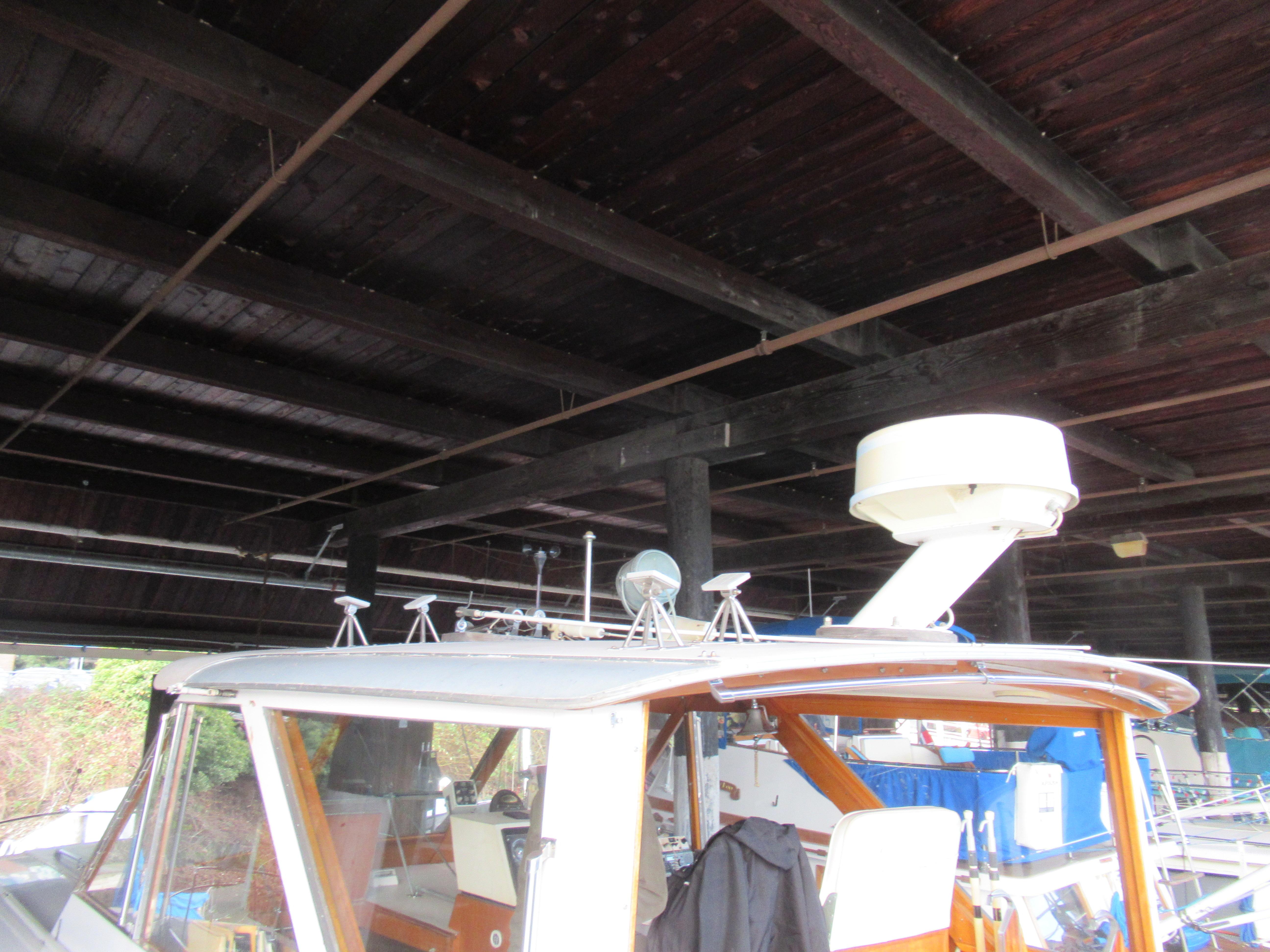 1963 Chris-Craft Constellation boat under a wooden dock, showcasing radar equipment.