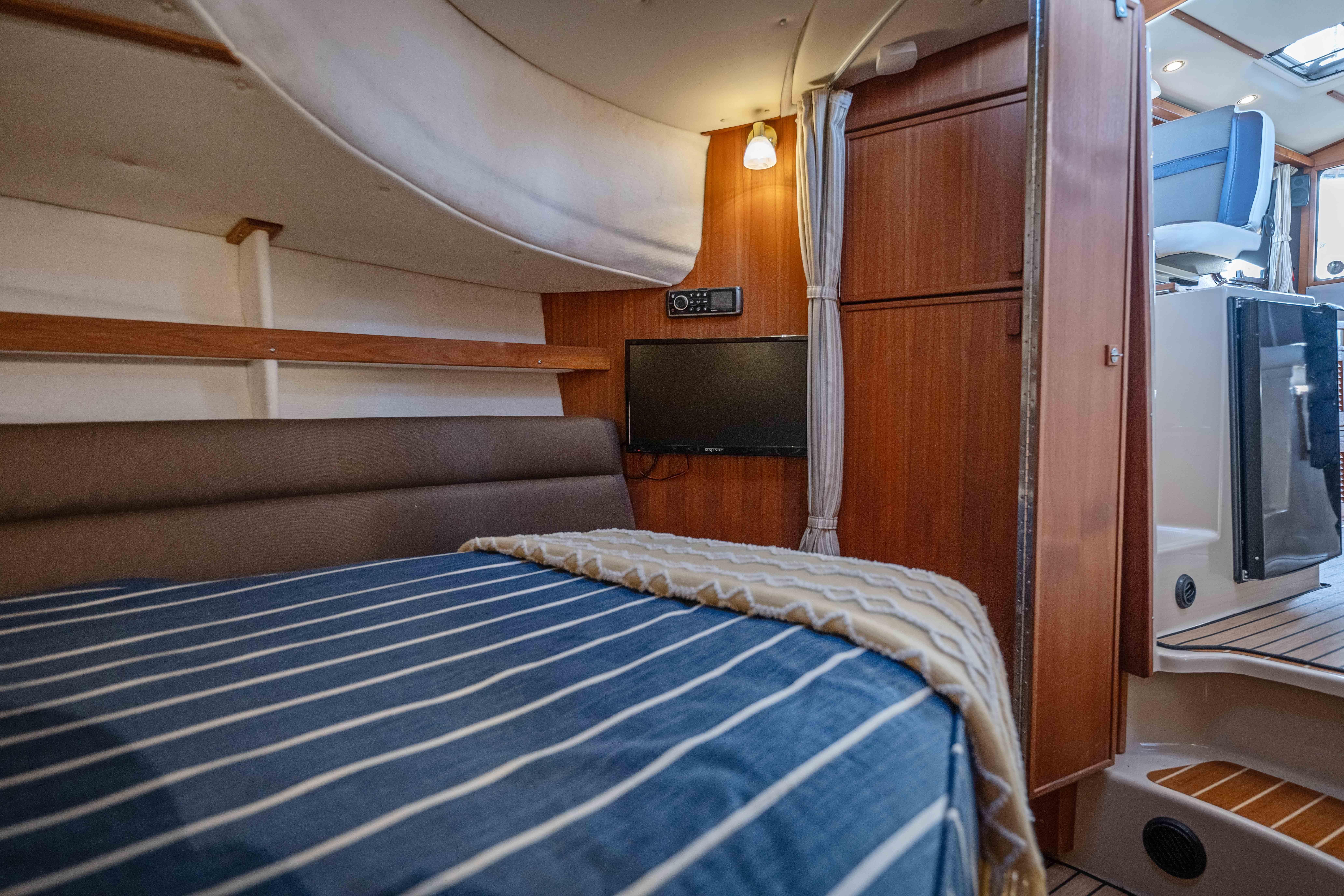 Cozy cabin interior of 2014 Ranger Tug R-31 CB with striped bedding and wood paneling.