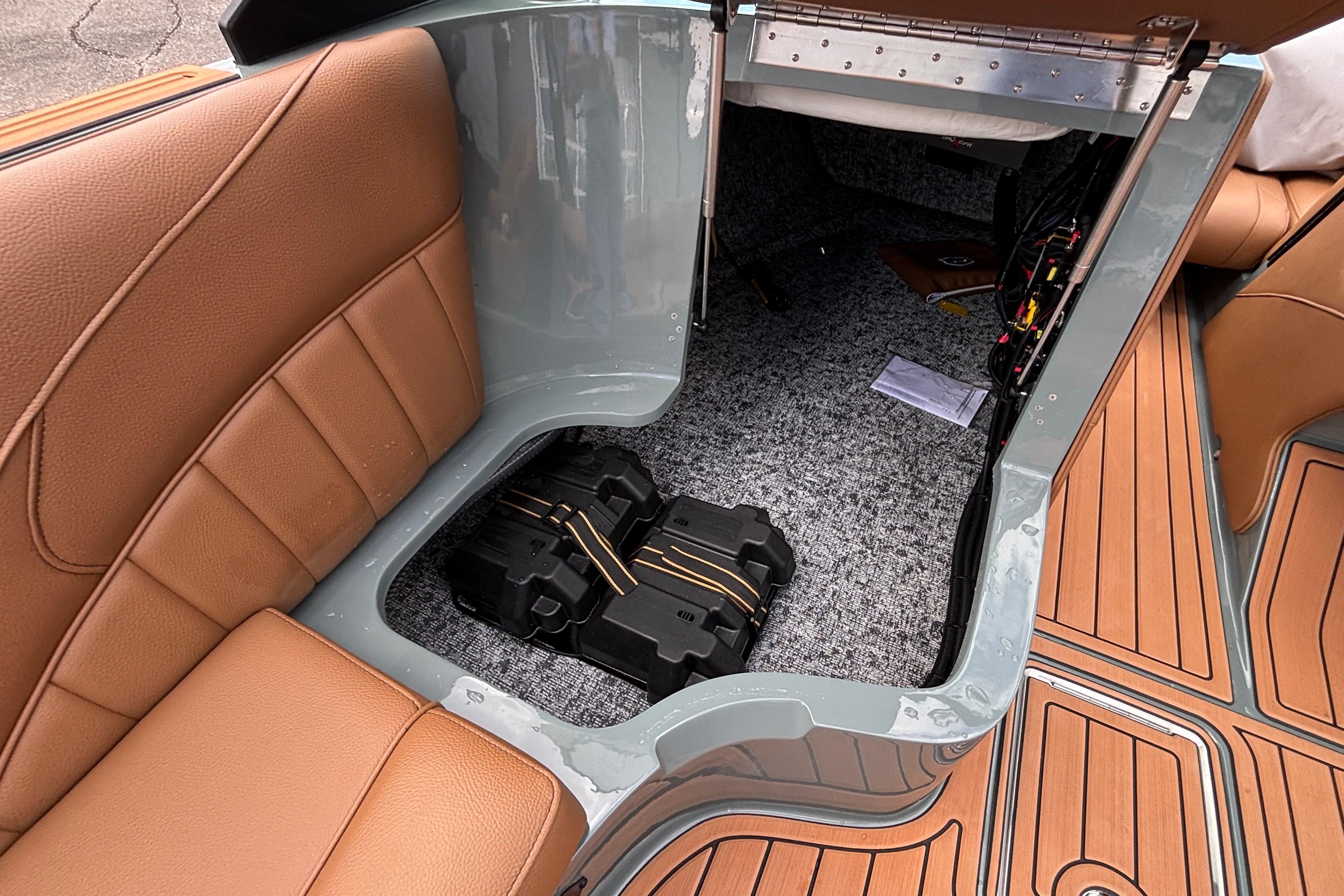 2026 MB B52 23 Classic boat interior storage with brown seating and visible battery compartment.