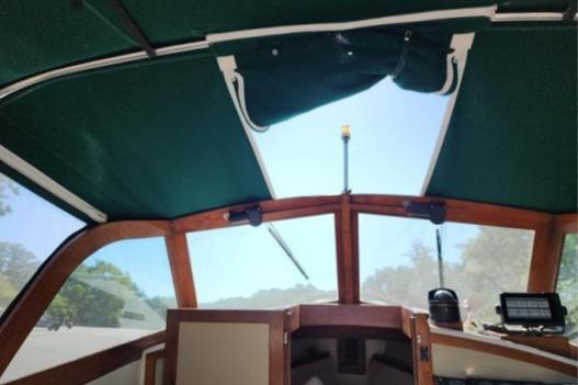 1985 Wasque Down East Cruiser interior with green canopy and wooden accents.