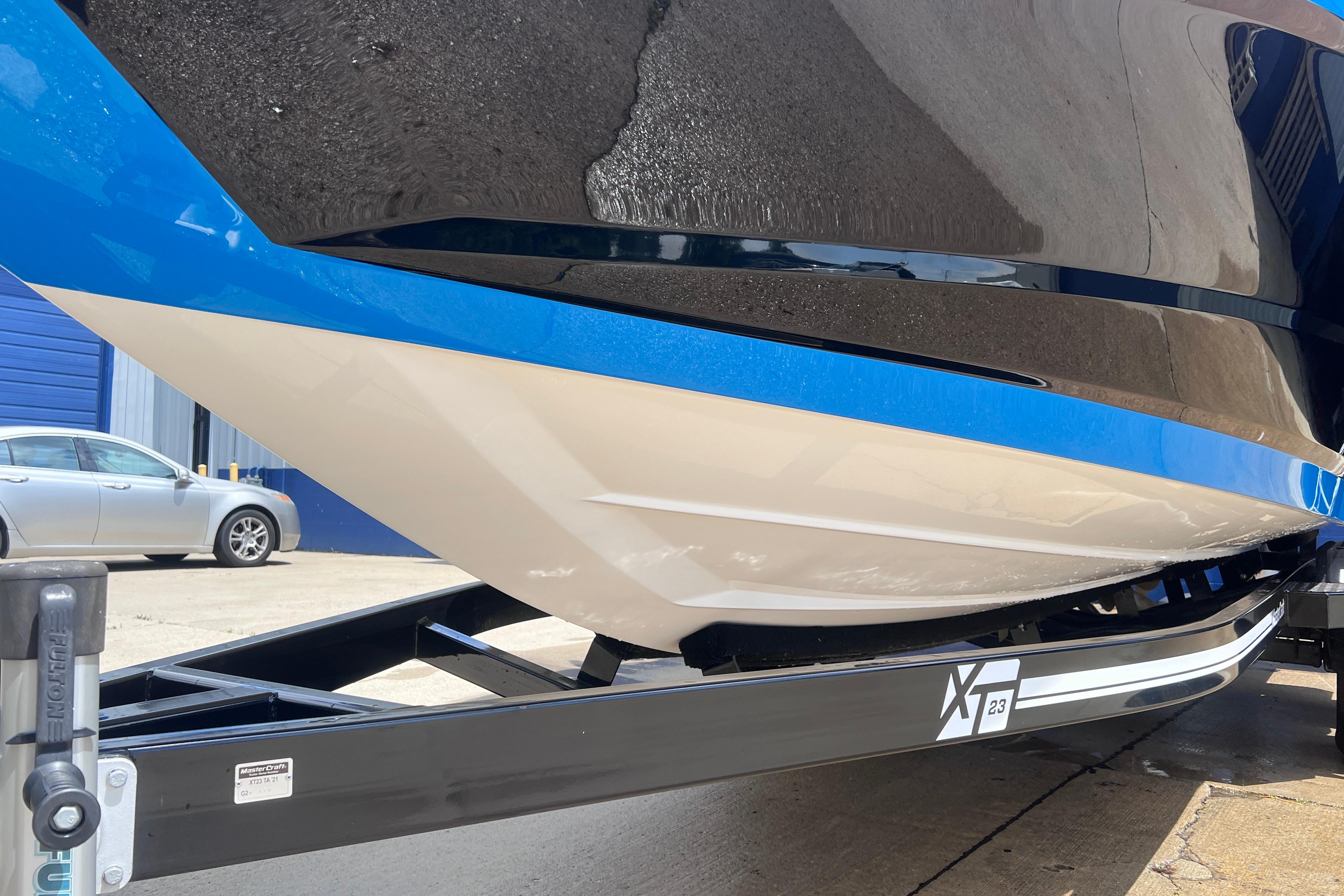 2021 MasterCraft XT23 boat on trailer, showcasing sleek hull design and vibrant blue accents.