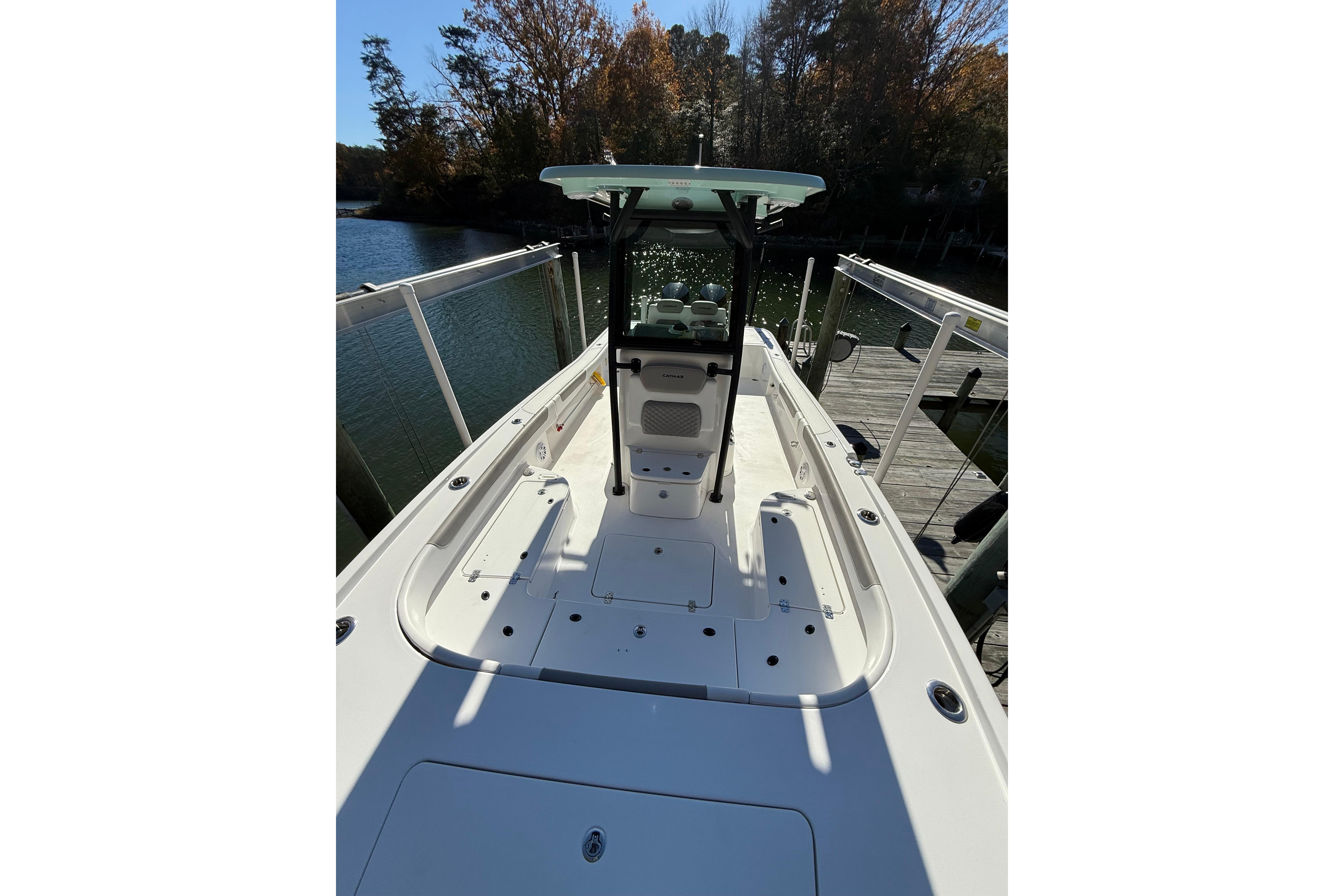 2023 Caymas 281 HB boat docked by a serene lake with autumn trees.