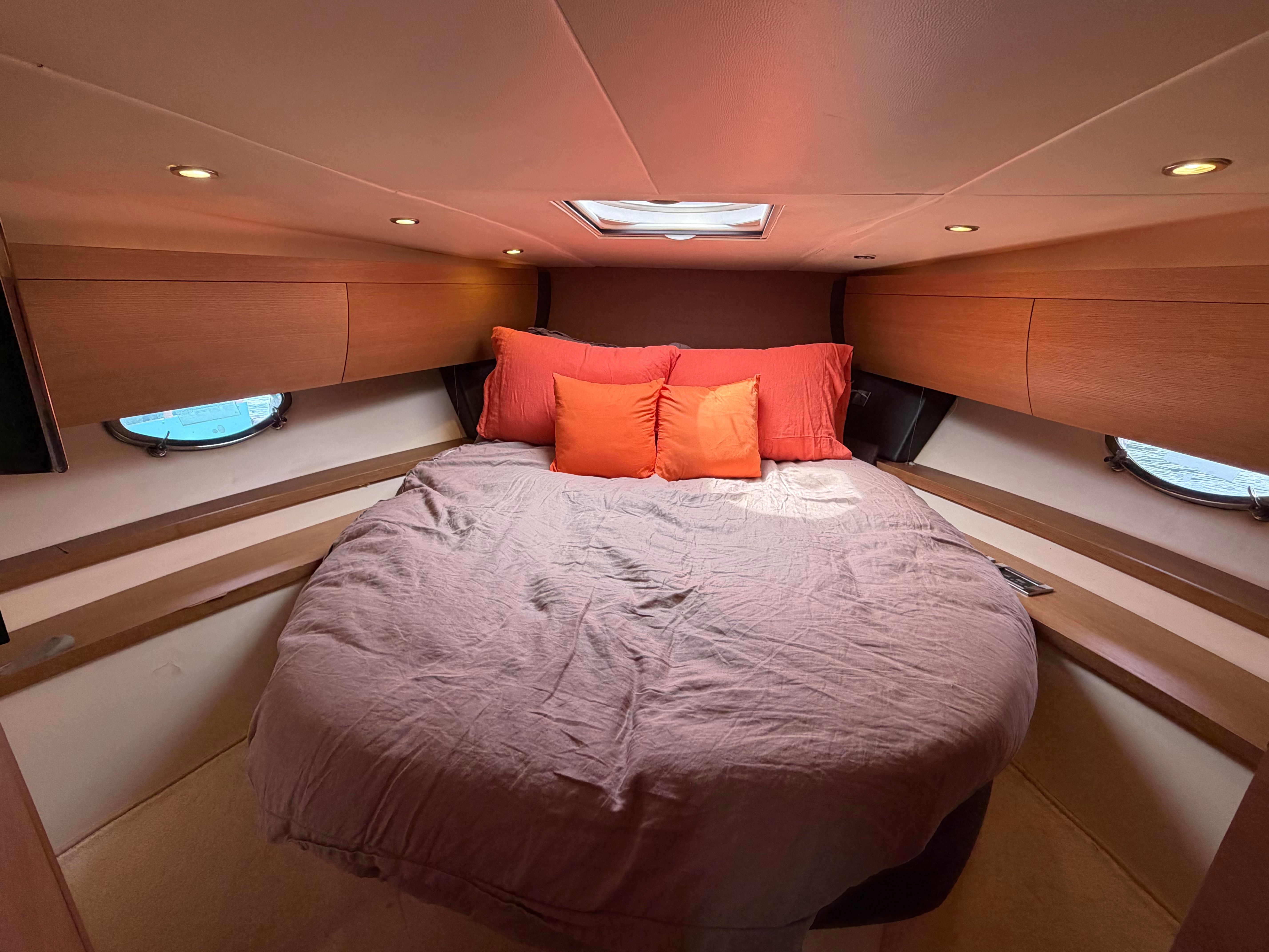 The image shows a cozy cabin with a large bed and orange pillows.