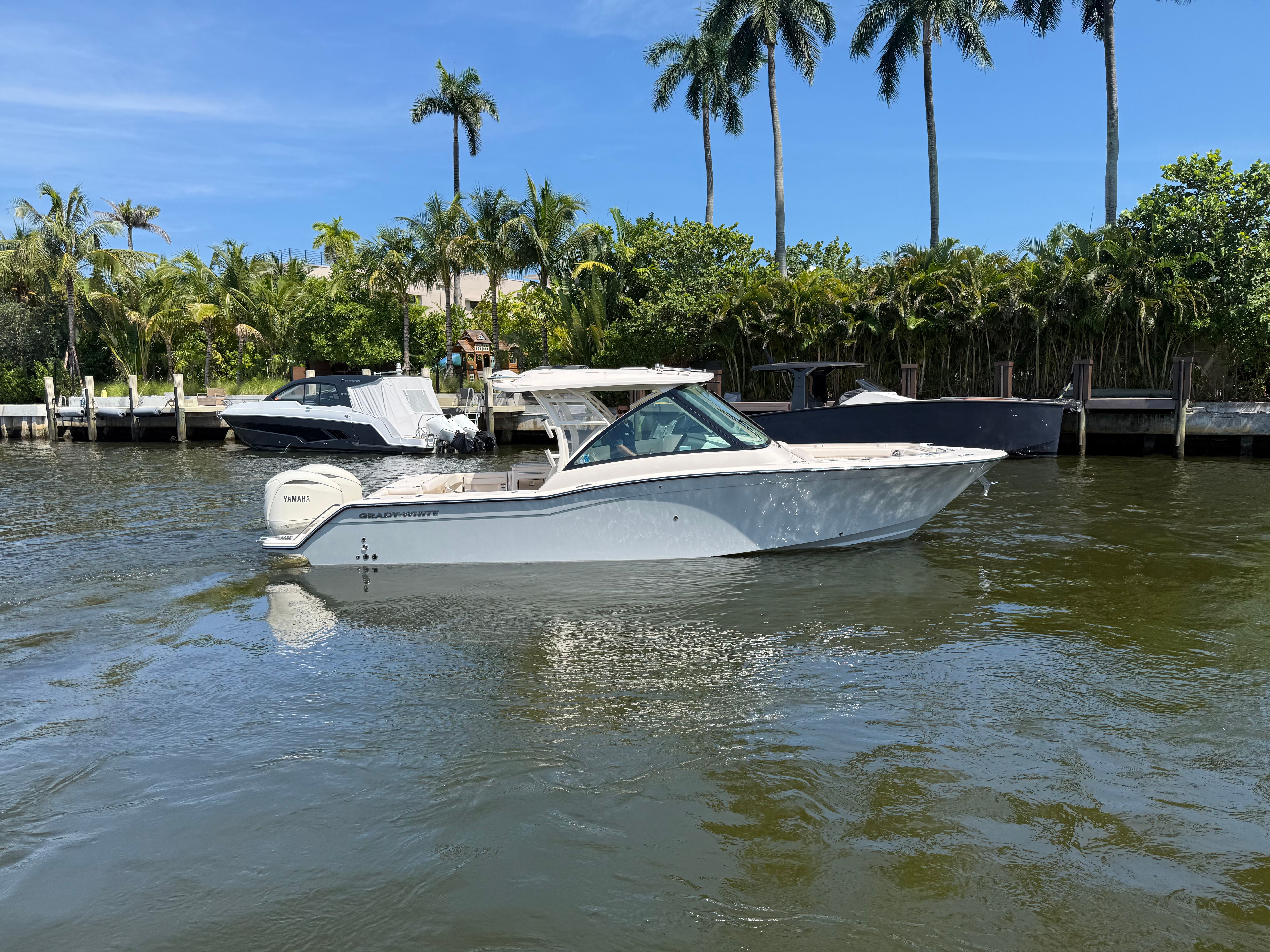 A Grady-White Freedom 325 boat on a calm waterway with palm trees in the background.